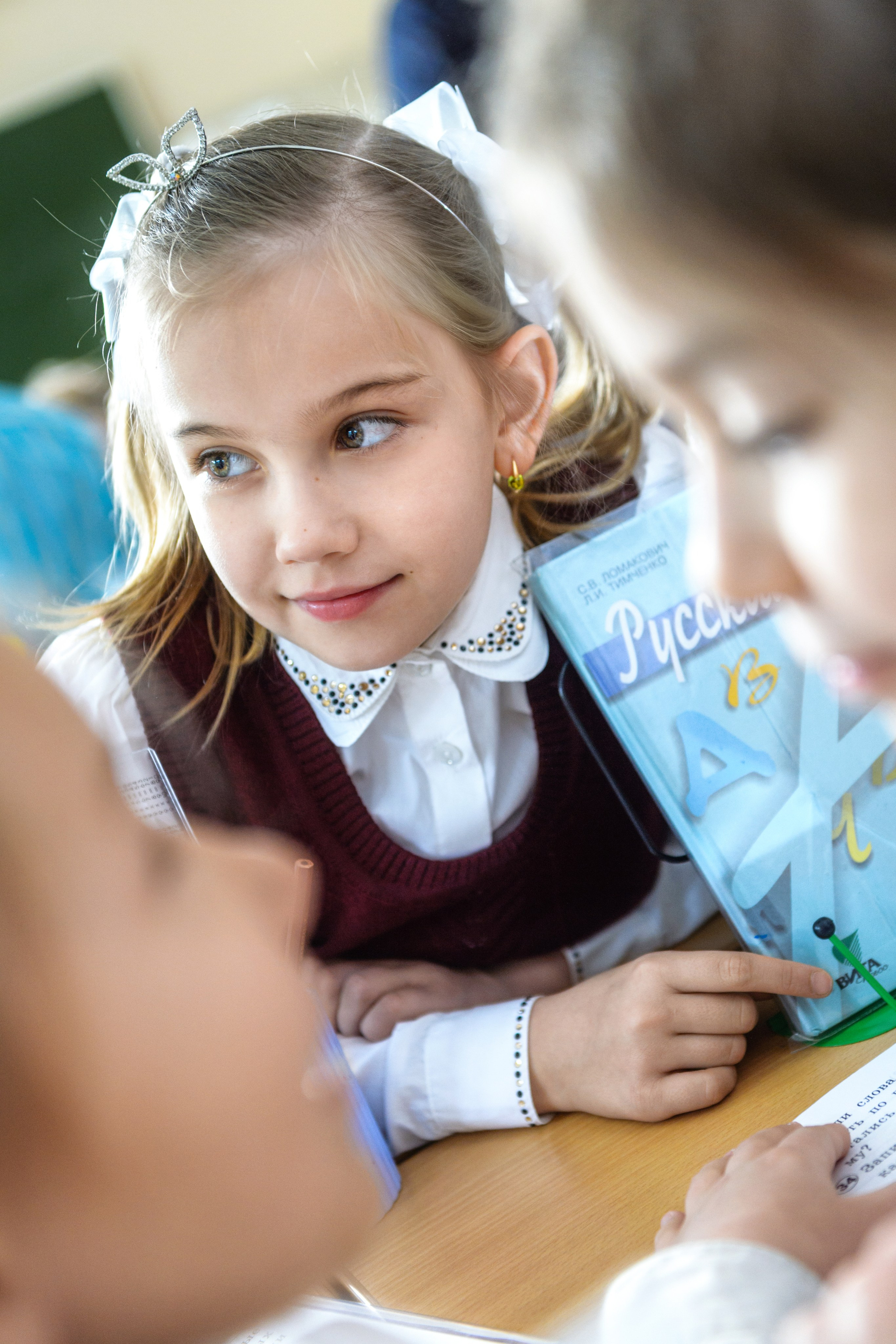 Девочка внимательно слушает объяснение за партой