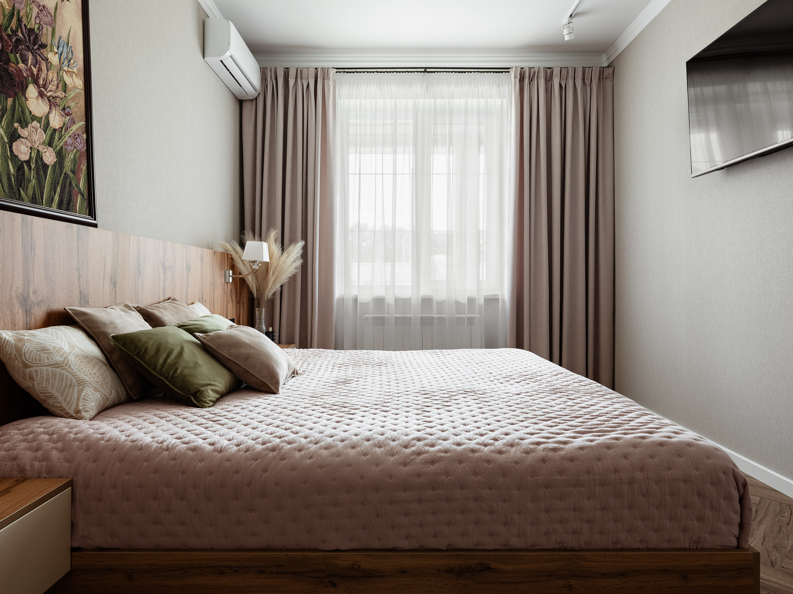 Светлая спальня с большим двуспальным ложем, розовым стёганым покрывалом, подушками в нейтральных тонах, деревянным изголовьем и плотными шторами, уютный современный интерьер, дизайнер Алина Чередниченко, фотограф Сергей Денисенко