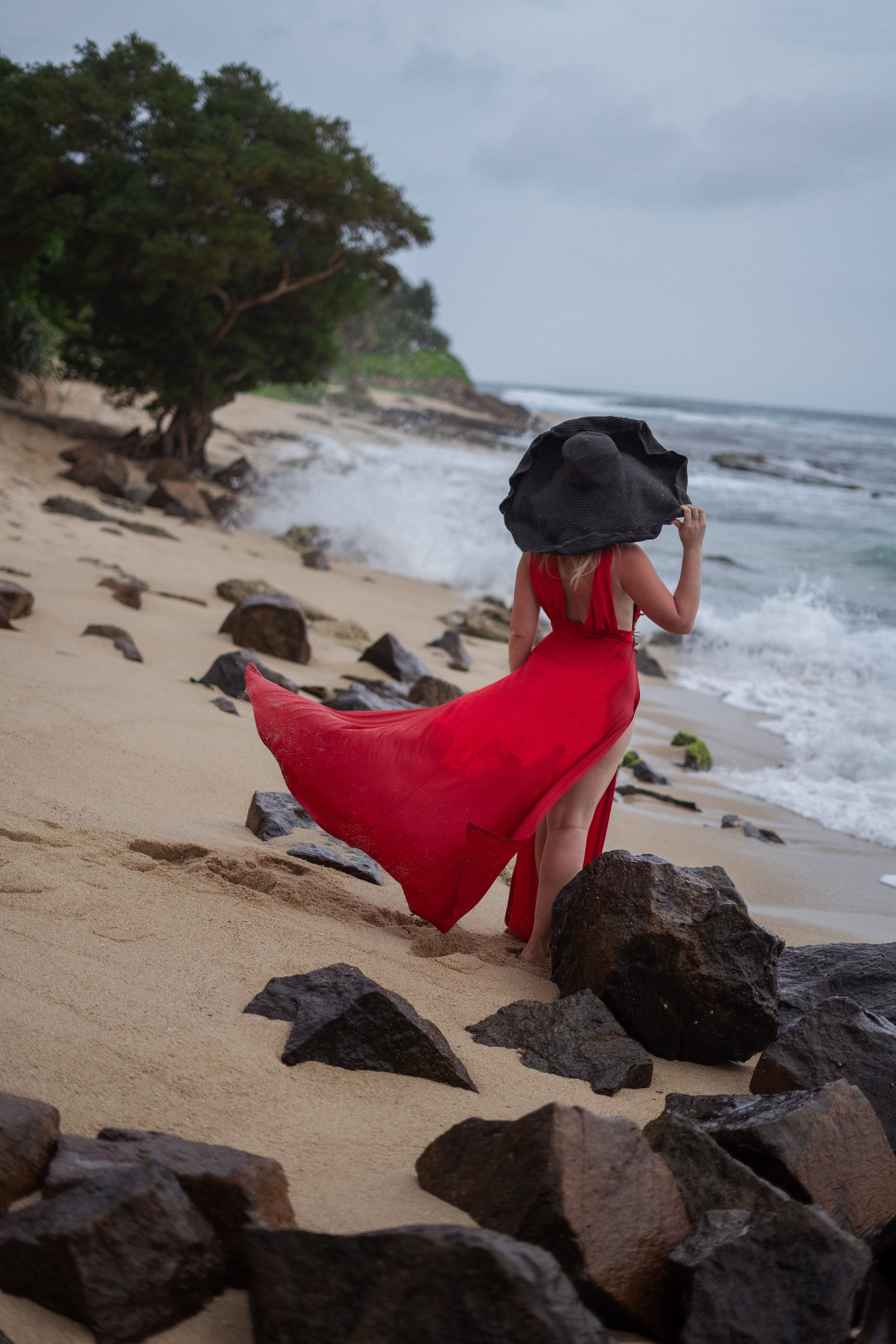 photoshoot of a beautiful blonde in a red dress by the ocean