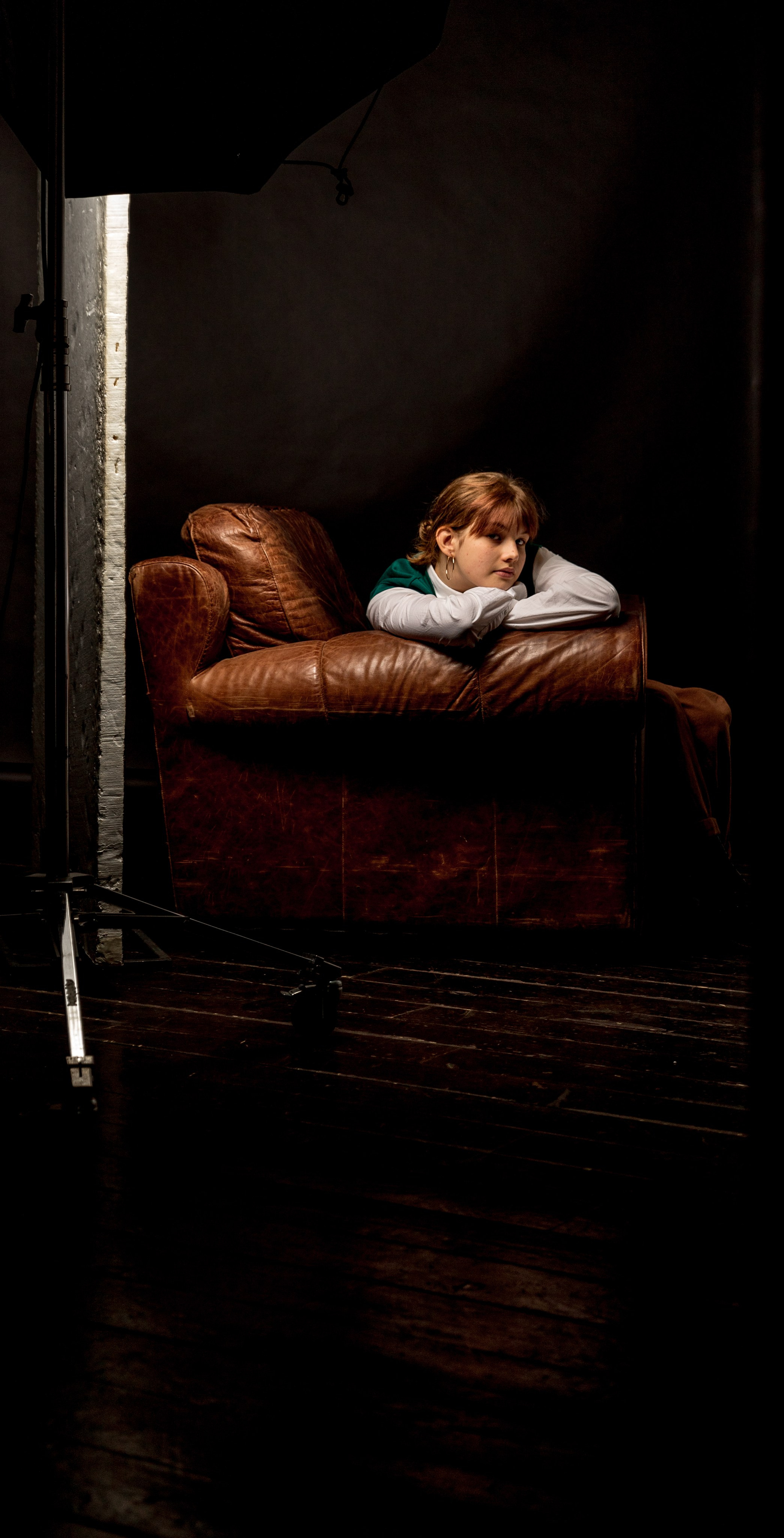 Девочка на кожаном диване в тёмной студии, драматический свет, Москва, Илья Антропов