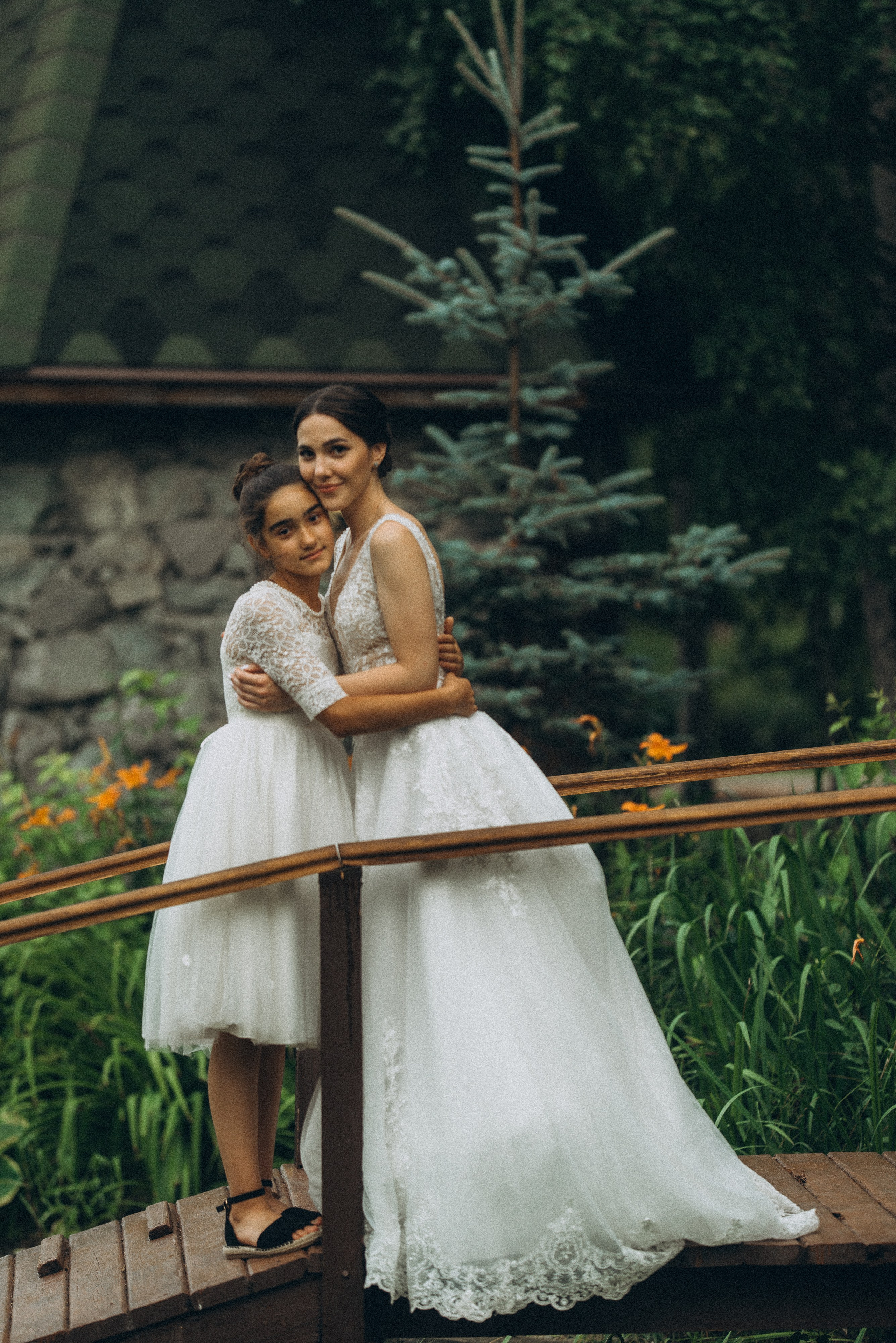 Сентиментальный момент: невеста Линда и девочка обнимаются на мостике. Свадебная фотография в Новосибирске.