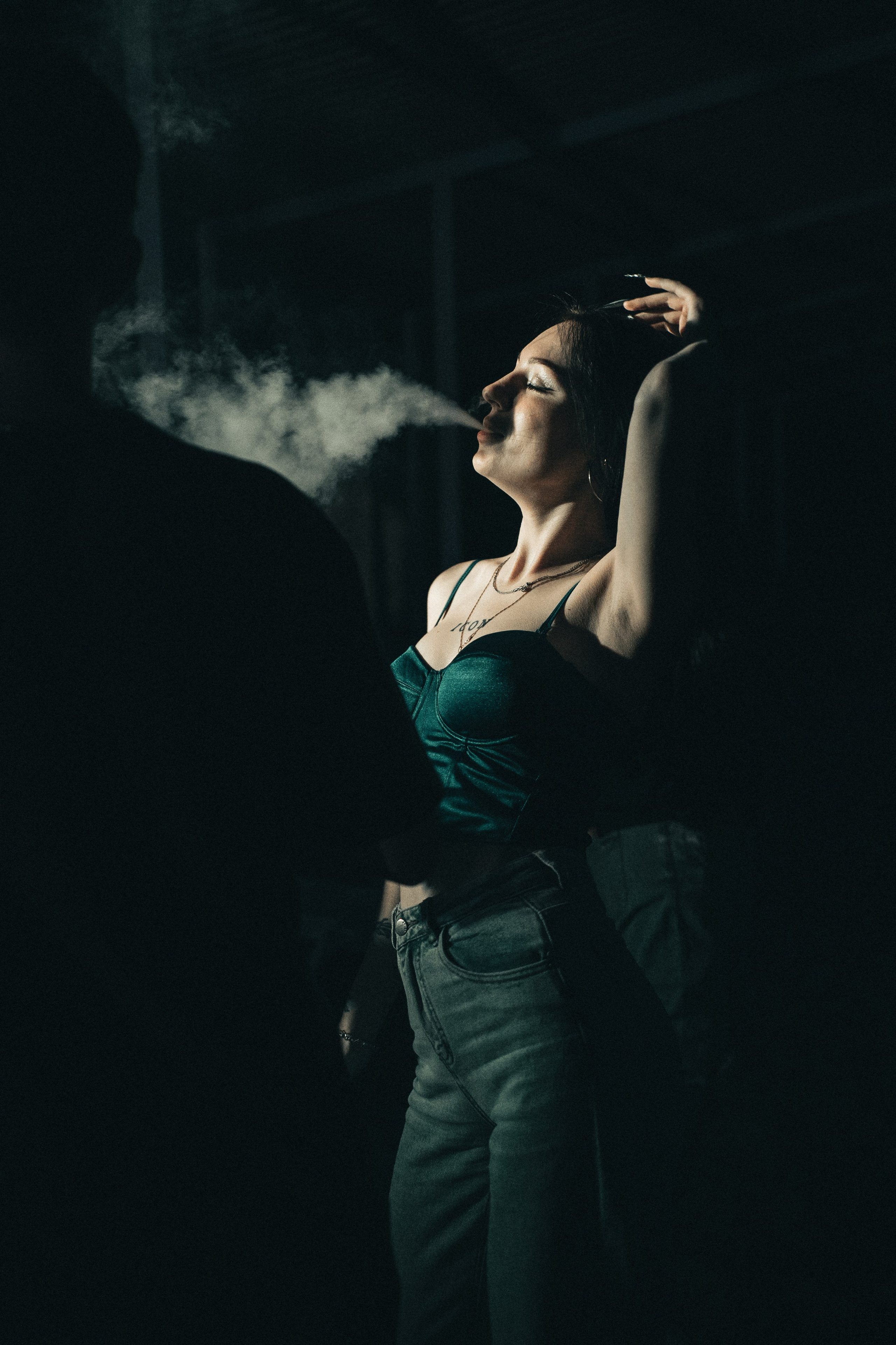 Молодая женщина выпускает пар от электронного устройства ночью на вечеринке