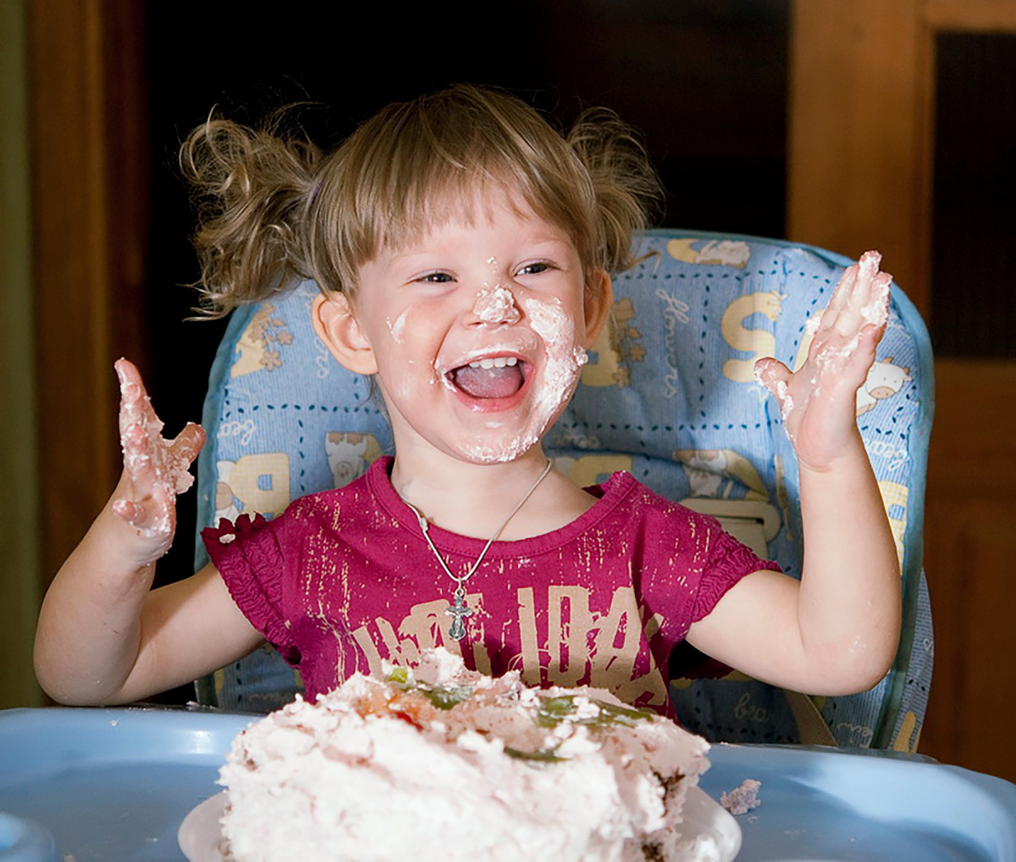 Ребёнок, пробующий первую порцию праздничного торта, с восторгом на лице