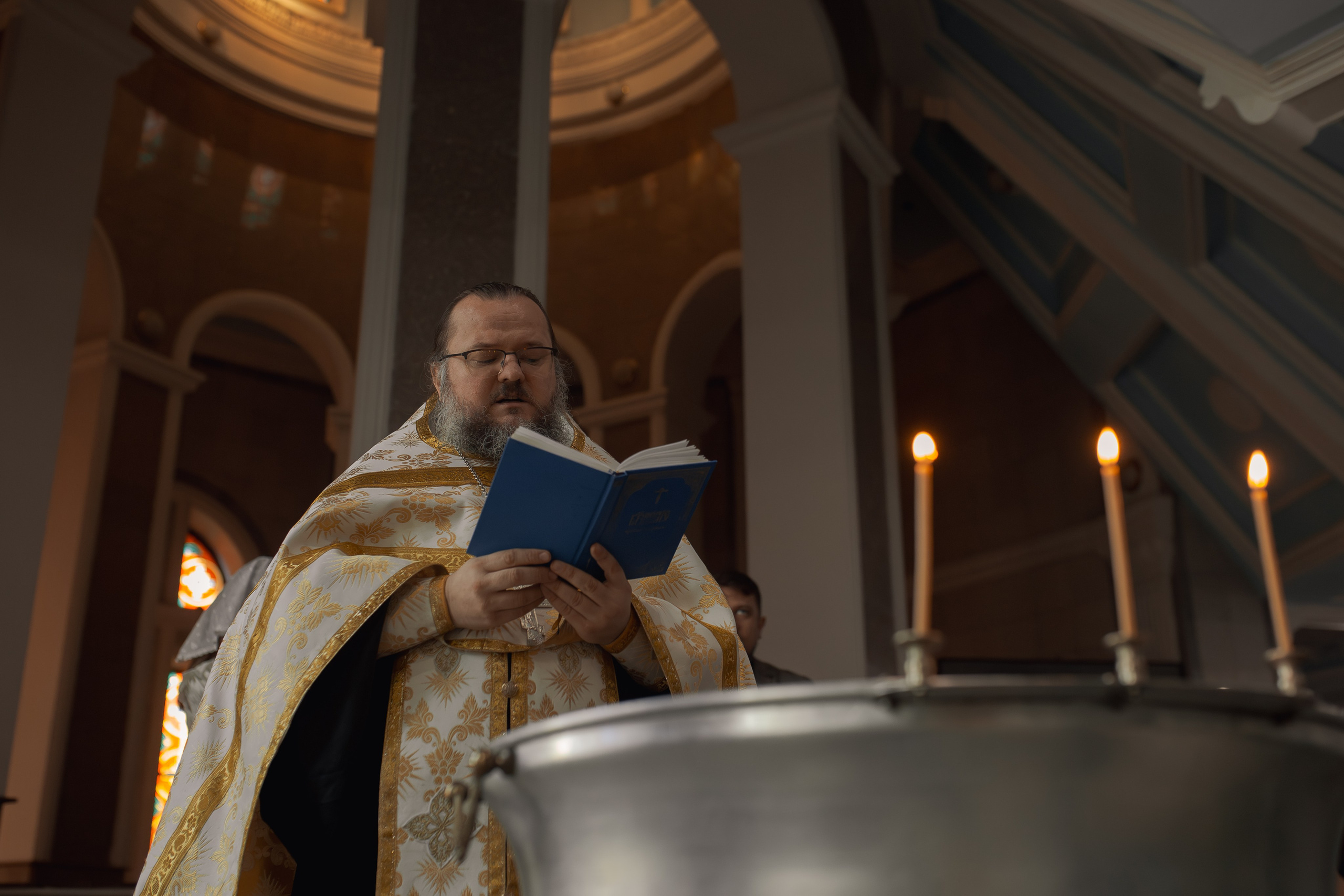 Иеромонах Михаил (Столяров) освящает воду в купели на крестинах в Ташкенте