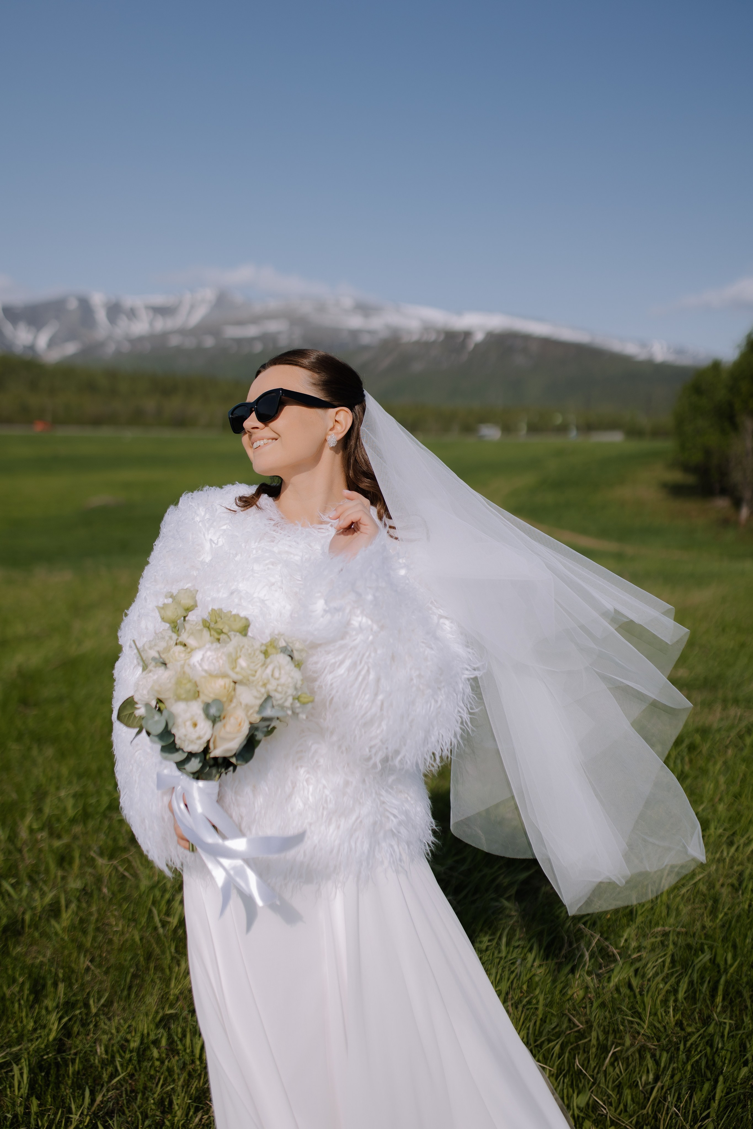Аккуратно уложенные волосы невесты развеваются на легком ветерке, вдыхающем ароматы хвойного леса.