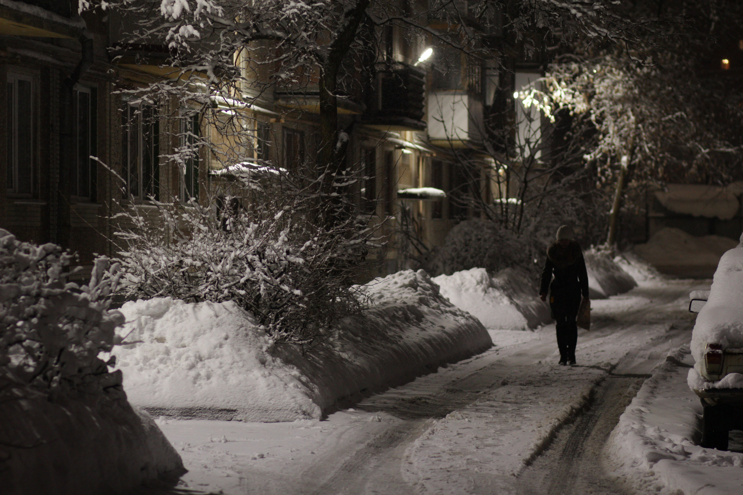 Зима в городе сугробы спальный район утро или вечер женщина идет мимо подъездов