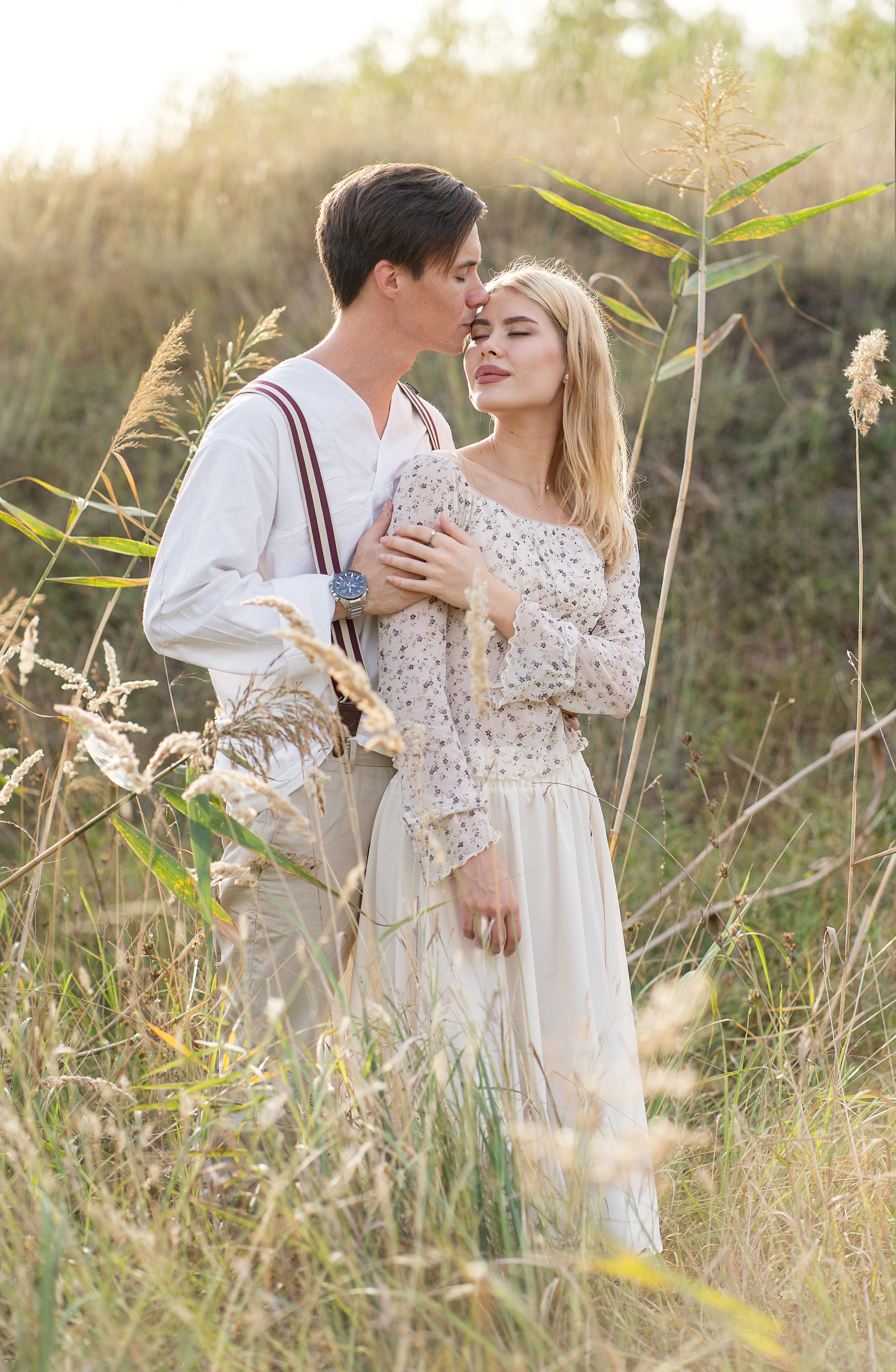 Влюбленная пара обнимается в поле, в камышах.