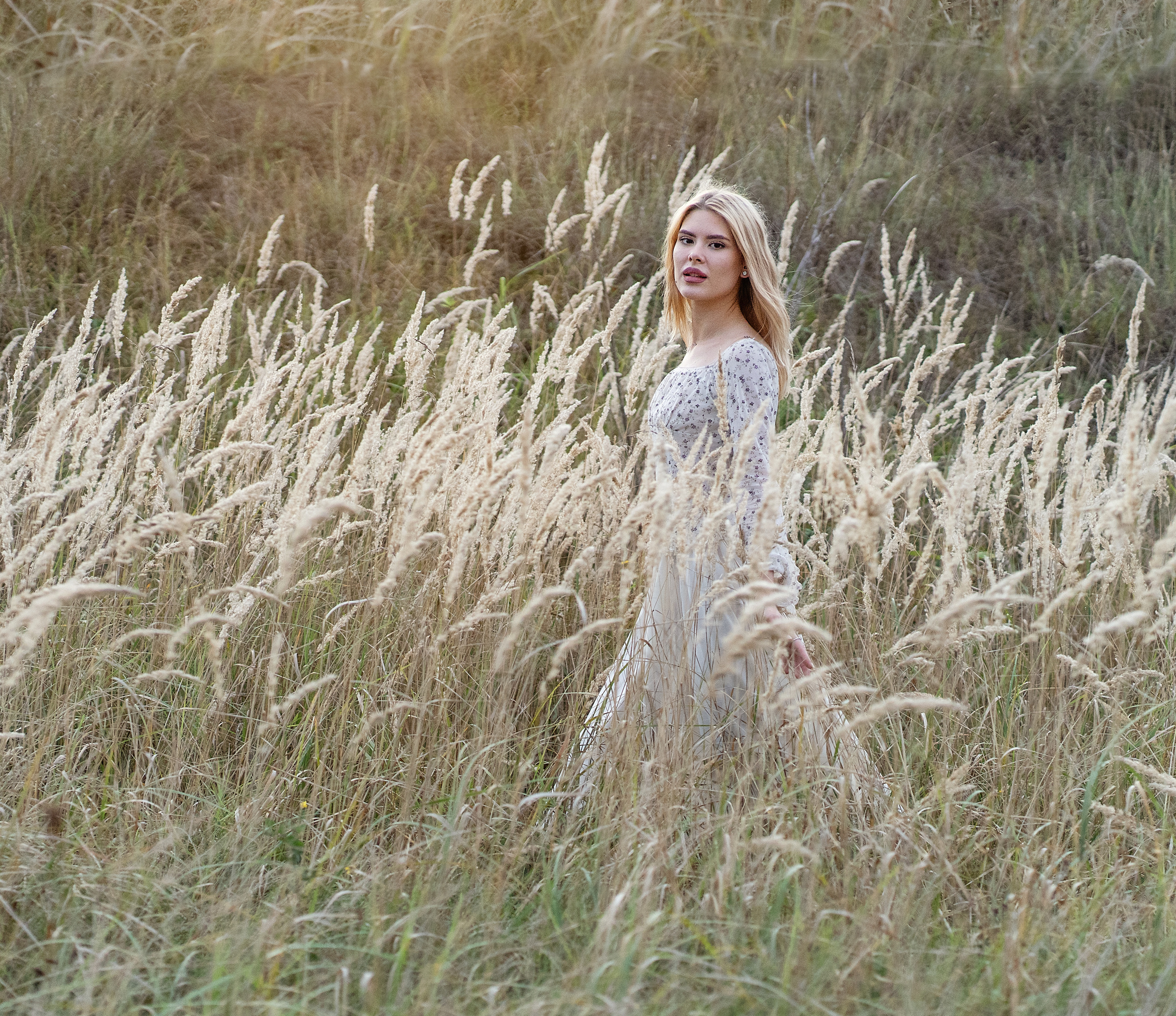 Девушка бежит свозь сухую траву.