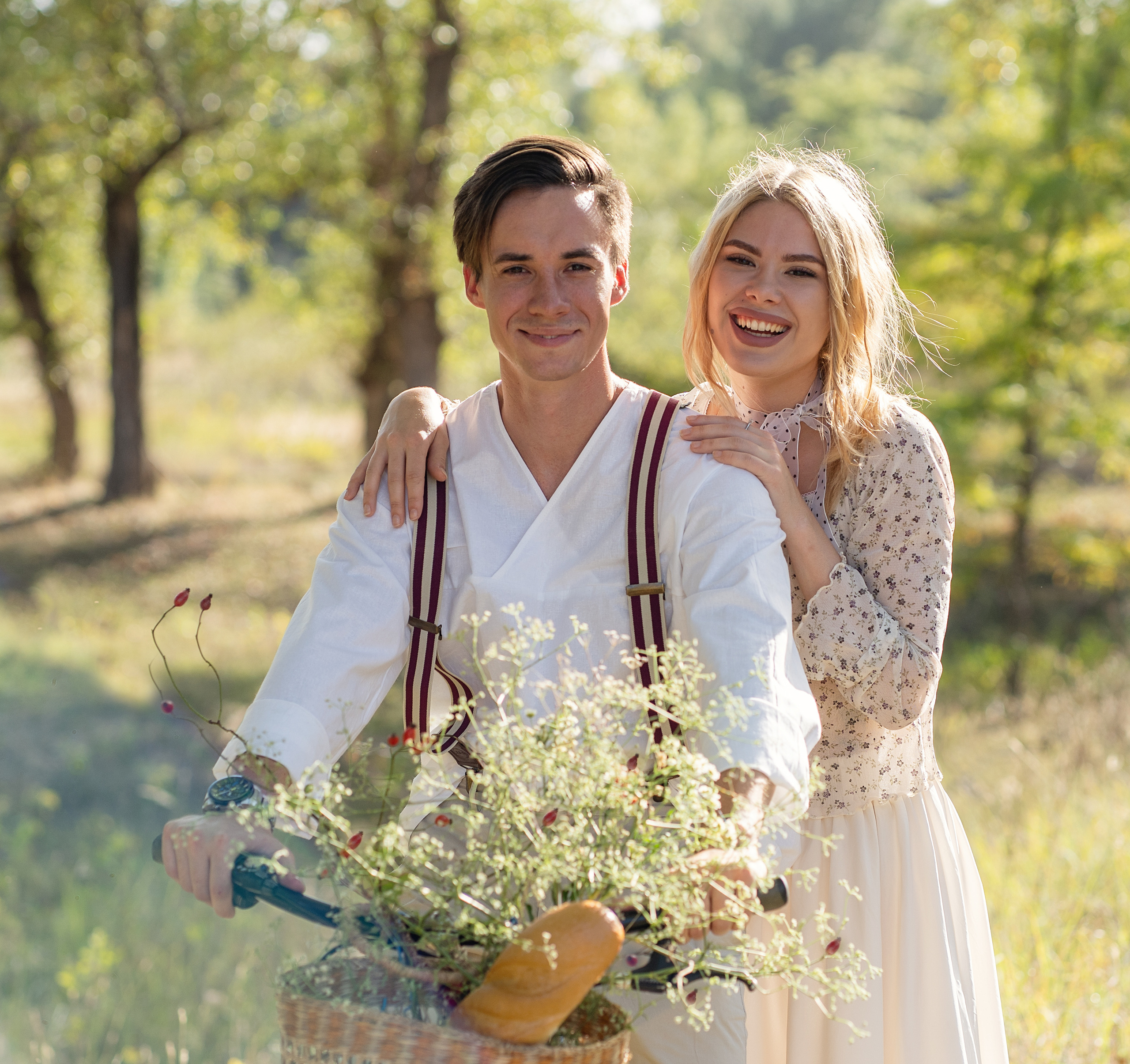 Пара на пикнике. Оба о чем-то смеются. На заднем фоне красивый лесю