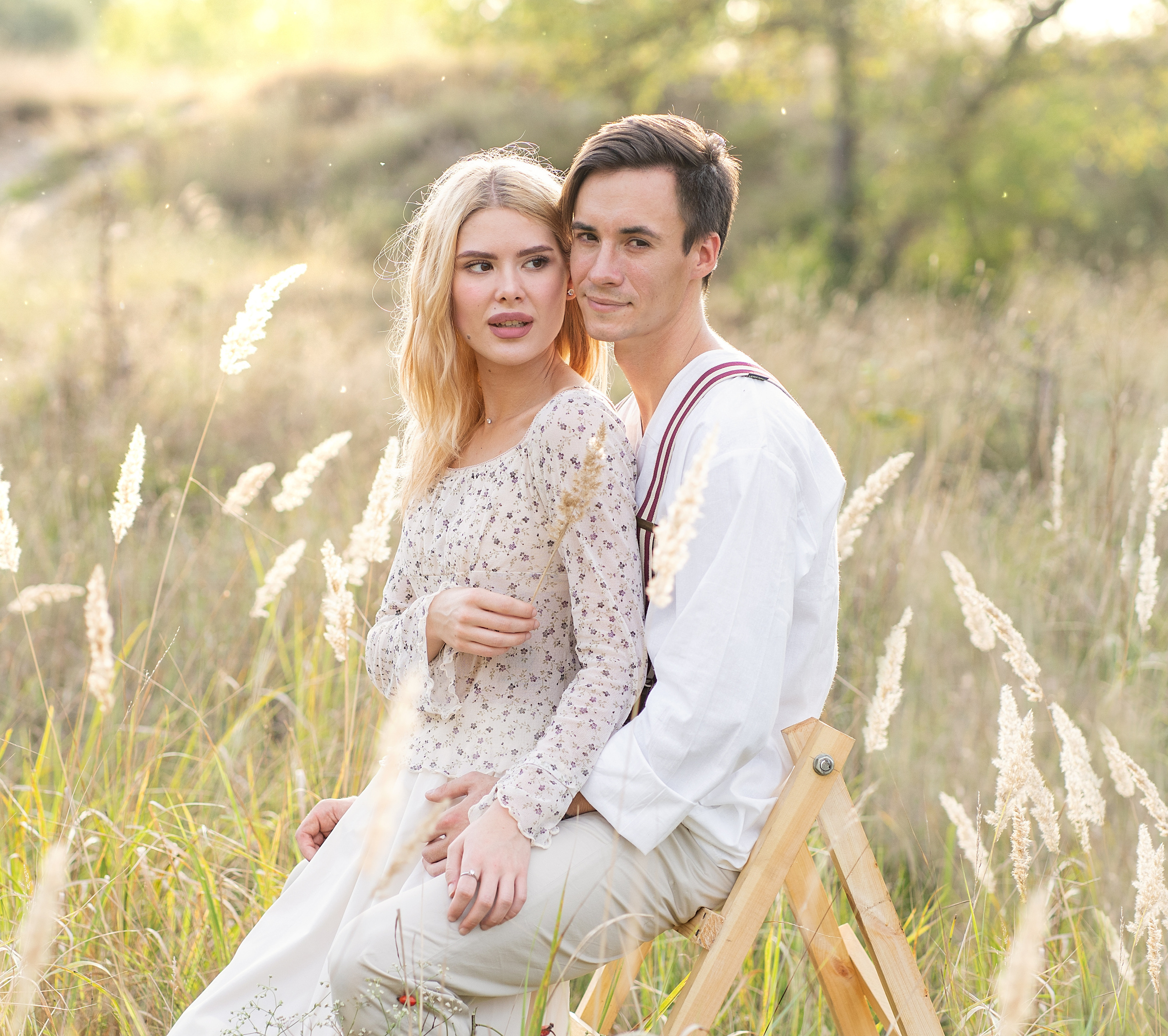 Девушка и парень сидят на стульчике среди сухостоя.