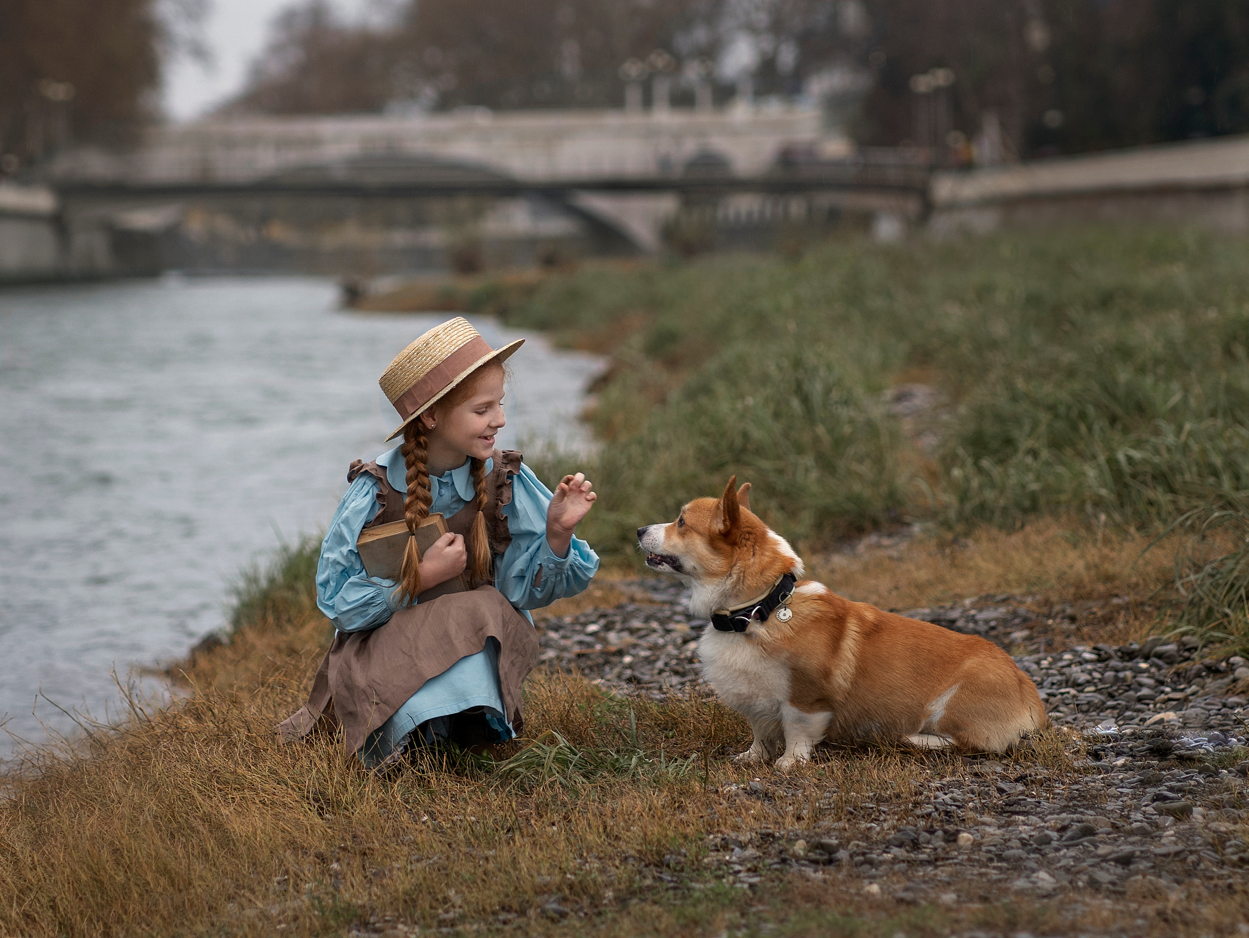 Девочка дрессирует свою собачку. Рядом течет река. Осенний пасмурный день.