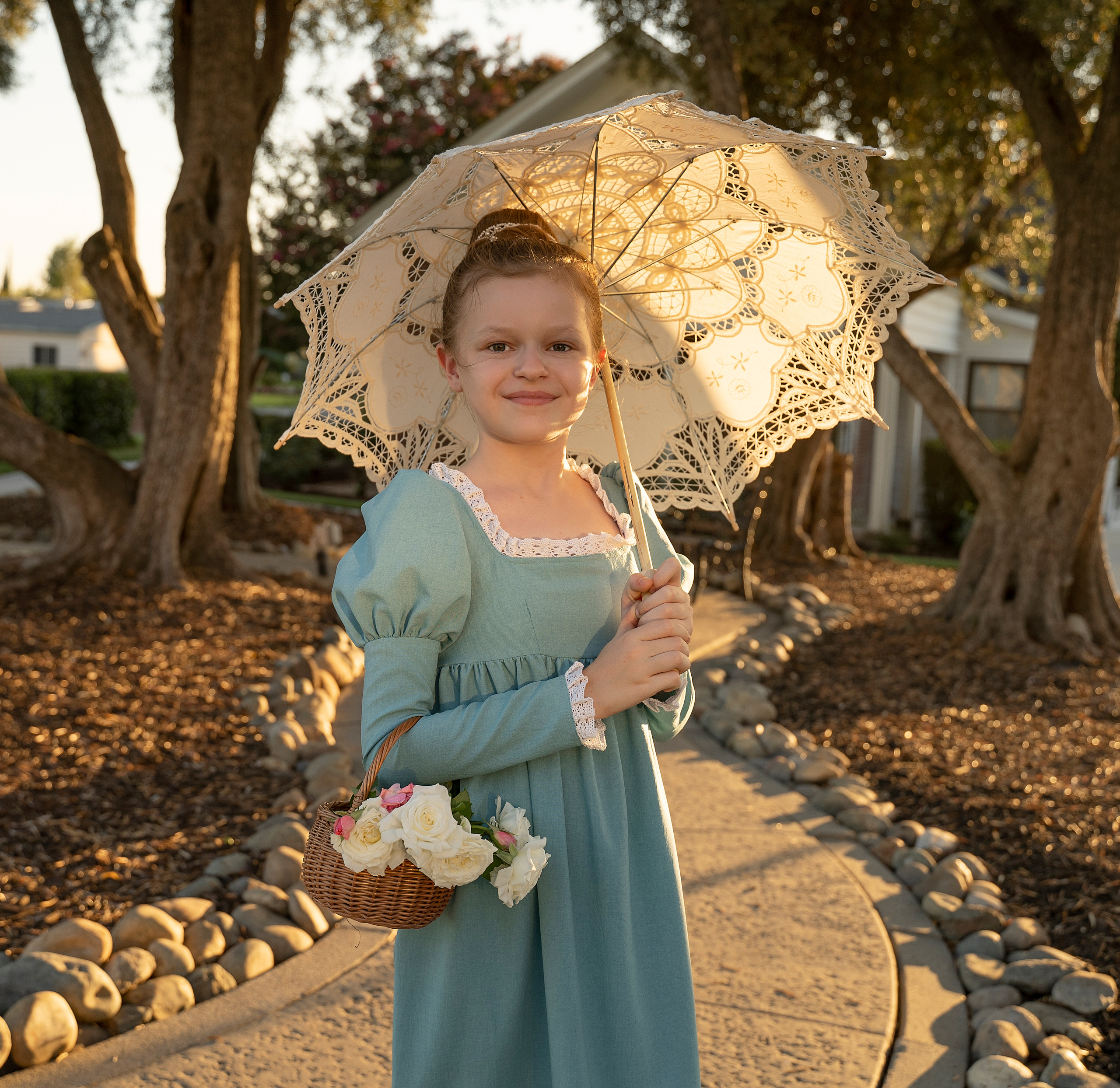 Девушка с белым зонтиком гуляет по аллее парка, в руках корзинка с розами.