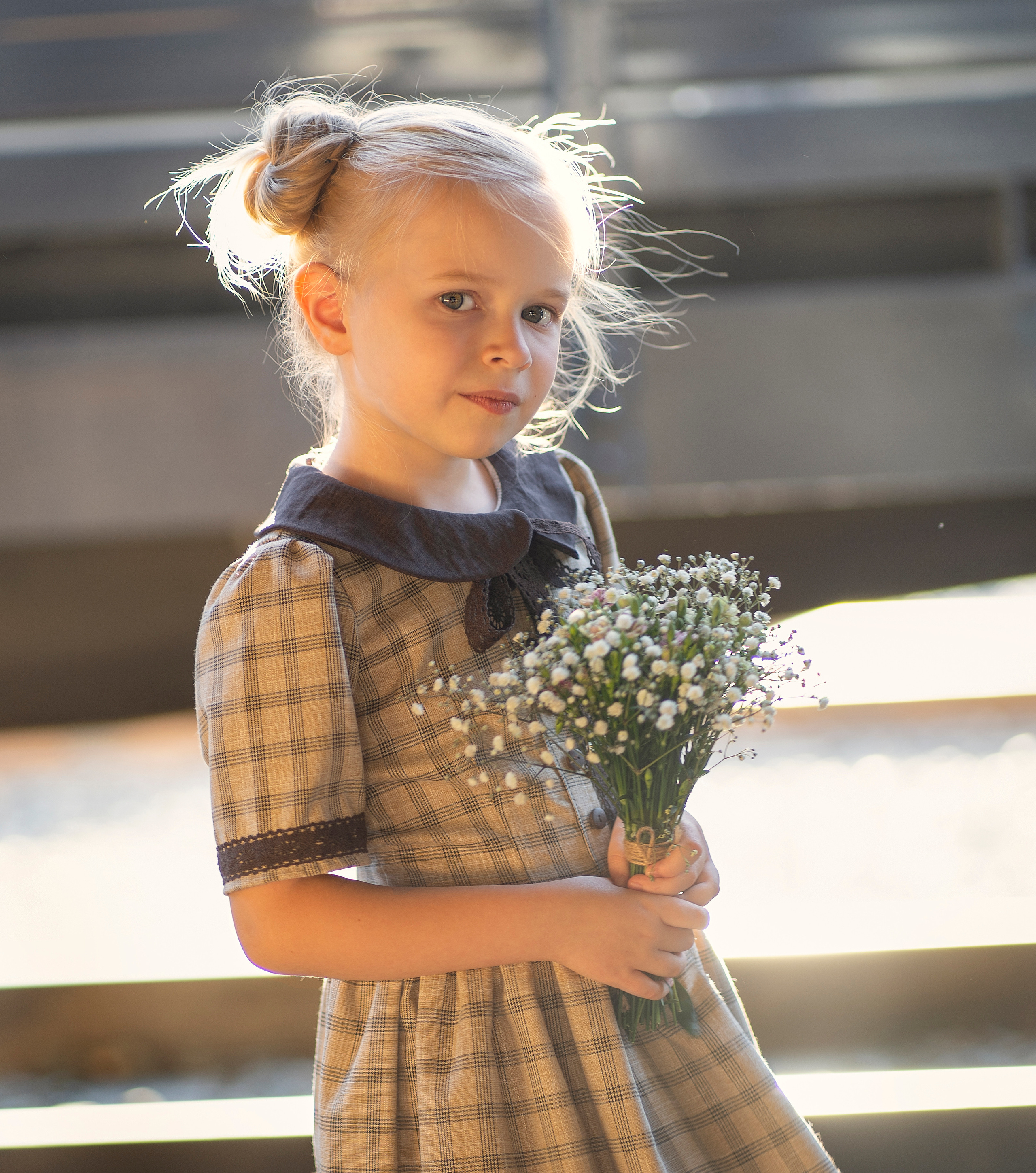 Девочка в лучах солнца, смотрит внимательно в даль. В руках букетик с белыми цветами.