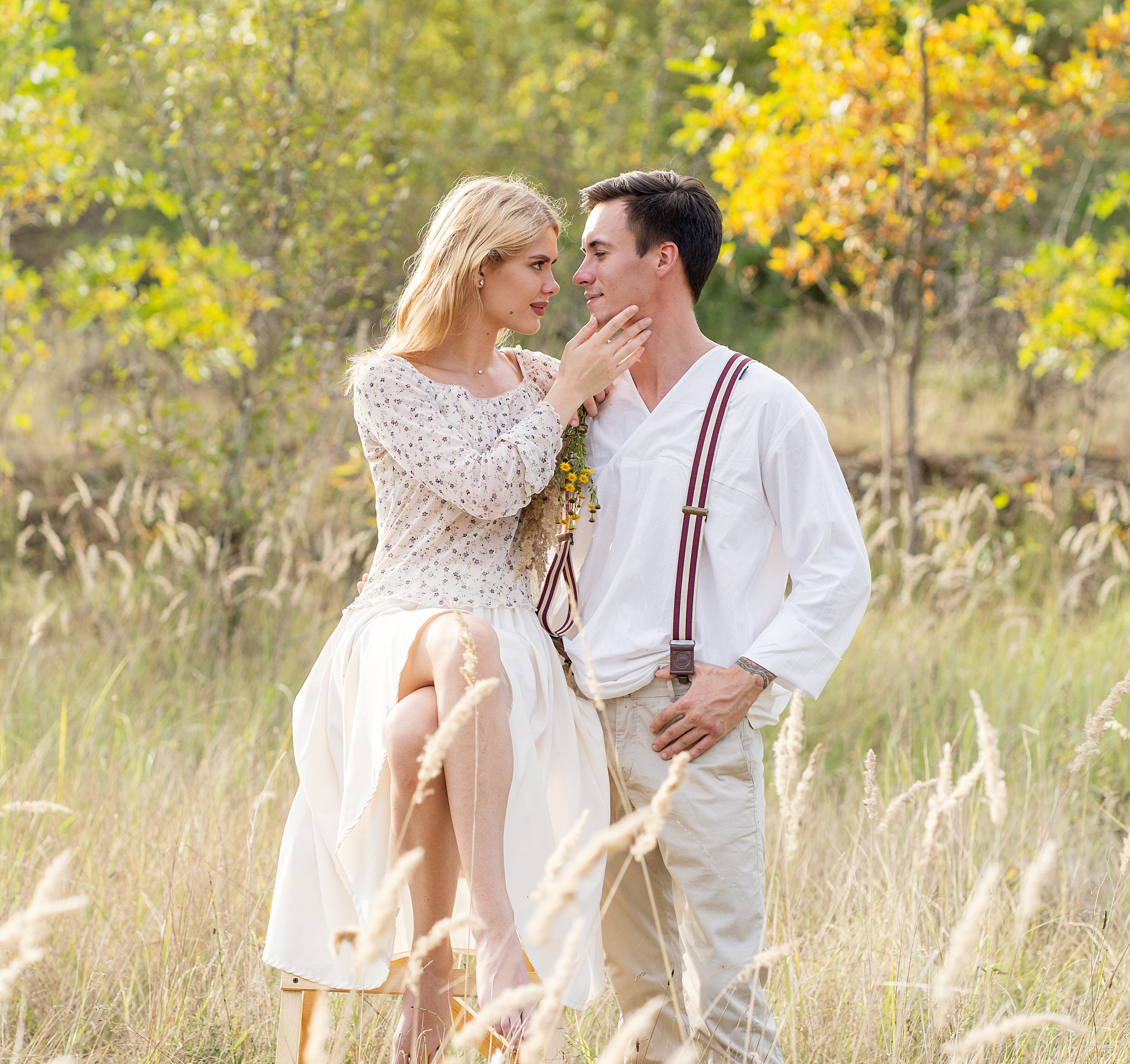 Влюбленные в поле, на фоне осеннего леса. Она смотрит на него в упор и гладит его подбородок.