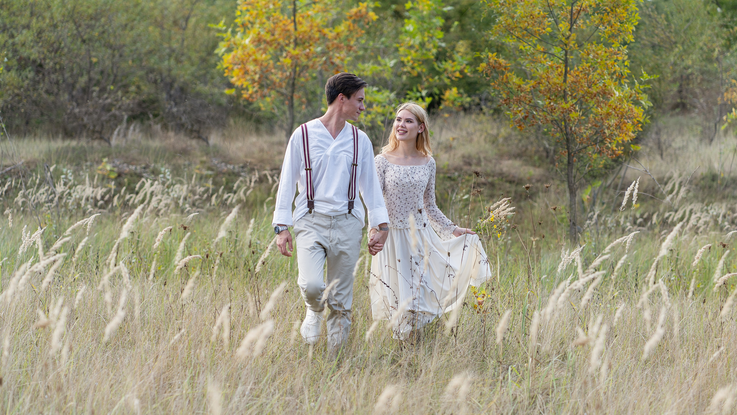 Парень и девушка идут по полю, сквозь камыши. Осень.