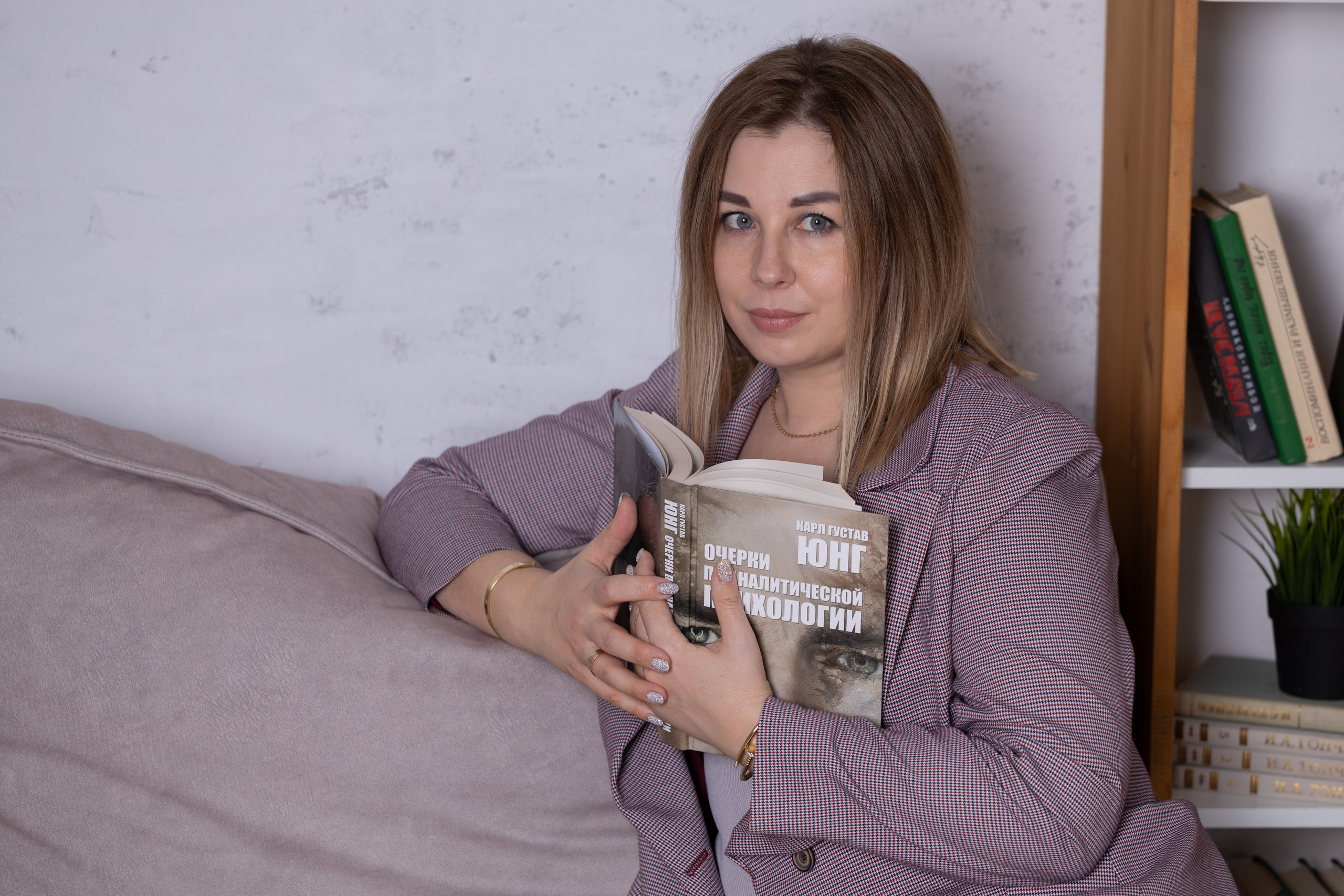 девушка сидит на диване с книгой в руках на фотосессии в студии