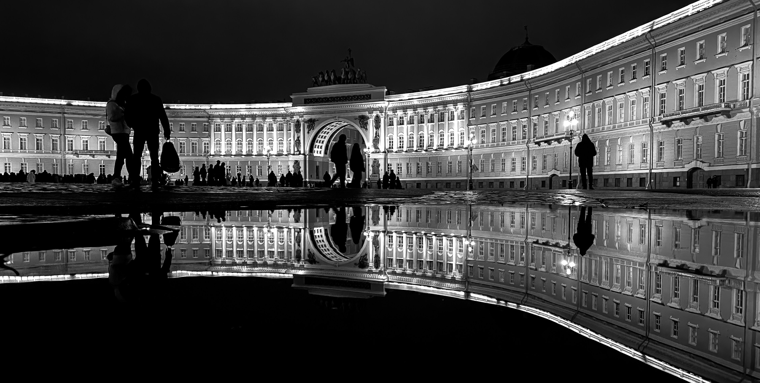  Ночная чёрно-белая фотография арки на Дворцовой площади Санкт-Петербурга, отражения в лужах, силуэты людей с пакетами, атмосферный городской пейзаж, Мальцев Евгений.