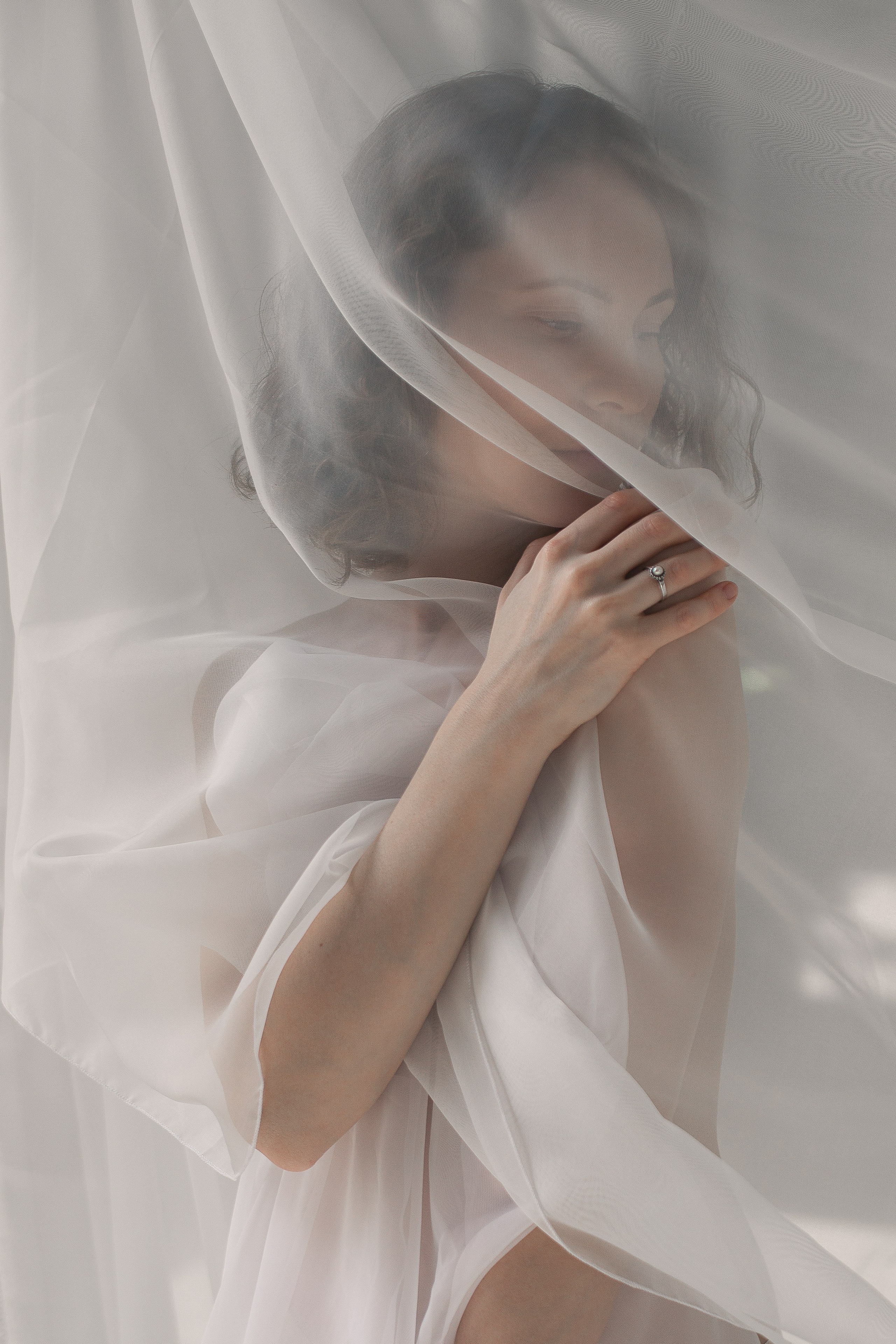 Портрет девушки с мягким светом от окна в студии, окутанной белой тканью.