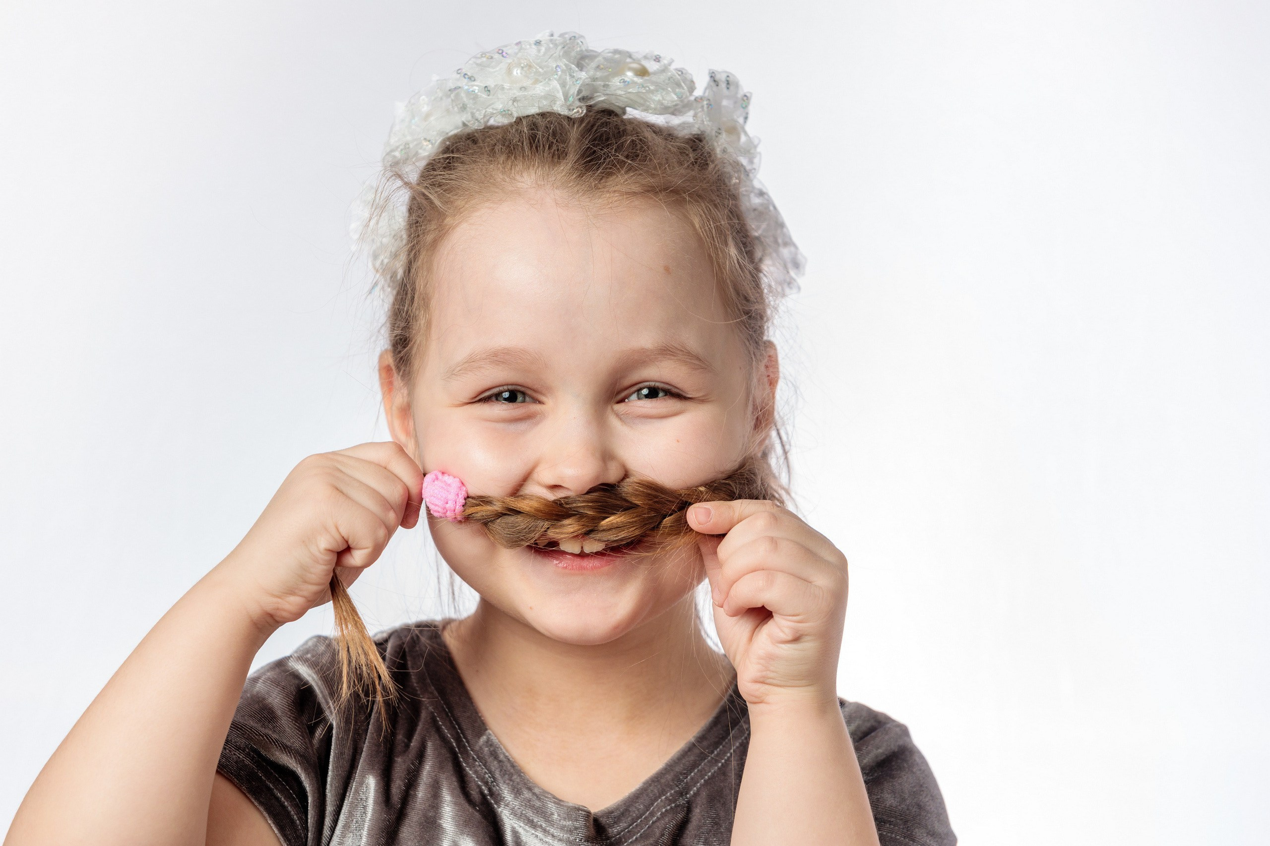 девочка делает усы из своей косички и весело смеется