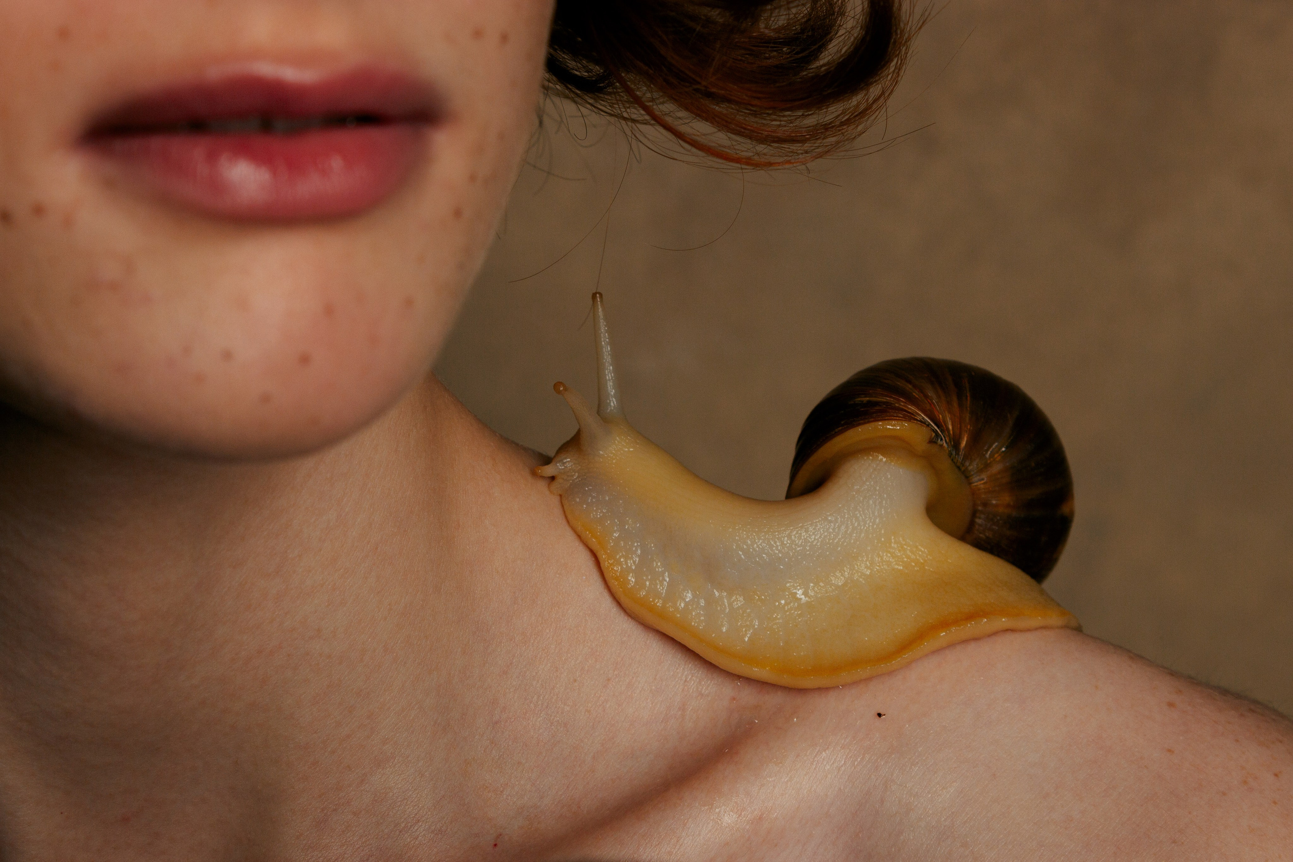 улитка Ахатина ползет по плече девушки