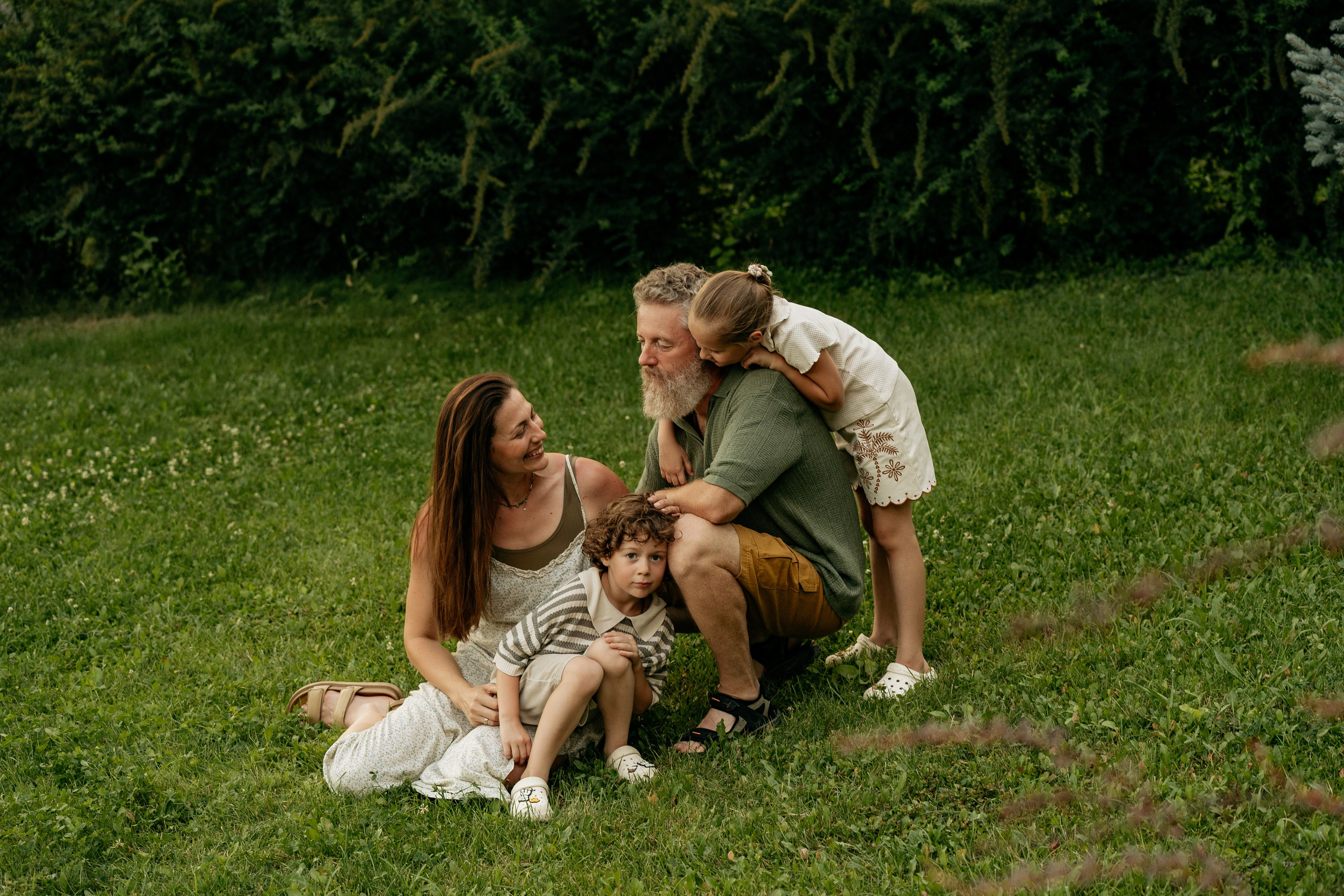 Мама, папа, сын и дочка смеются на лужайке в Абрау-Дюрсо