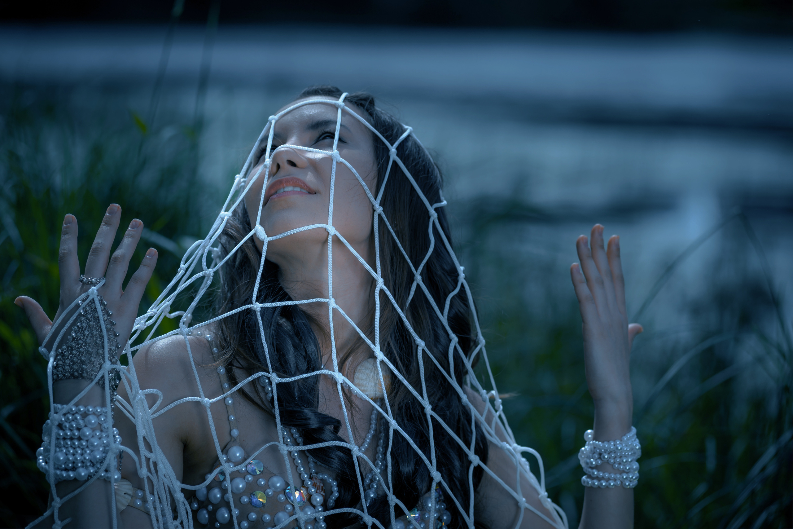 крупный портрет девушки освещенной луной окутанная сетями на берегу озера смотрит на небо