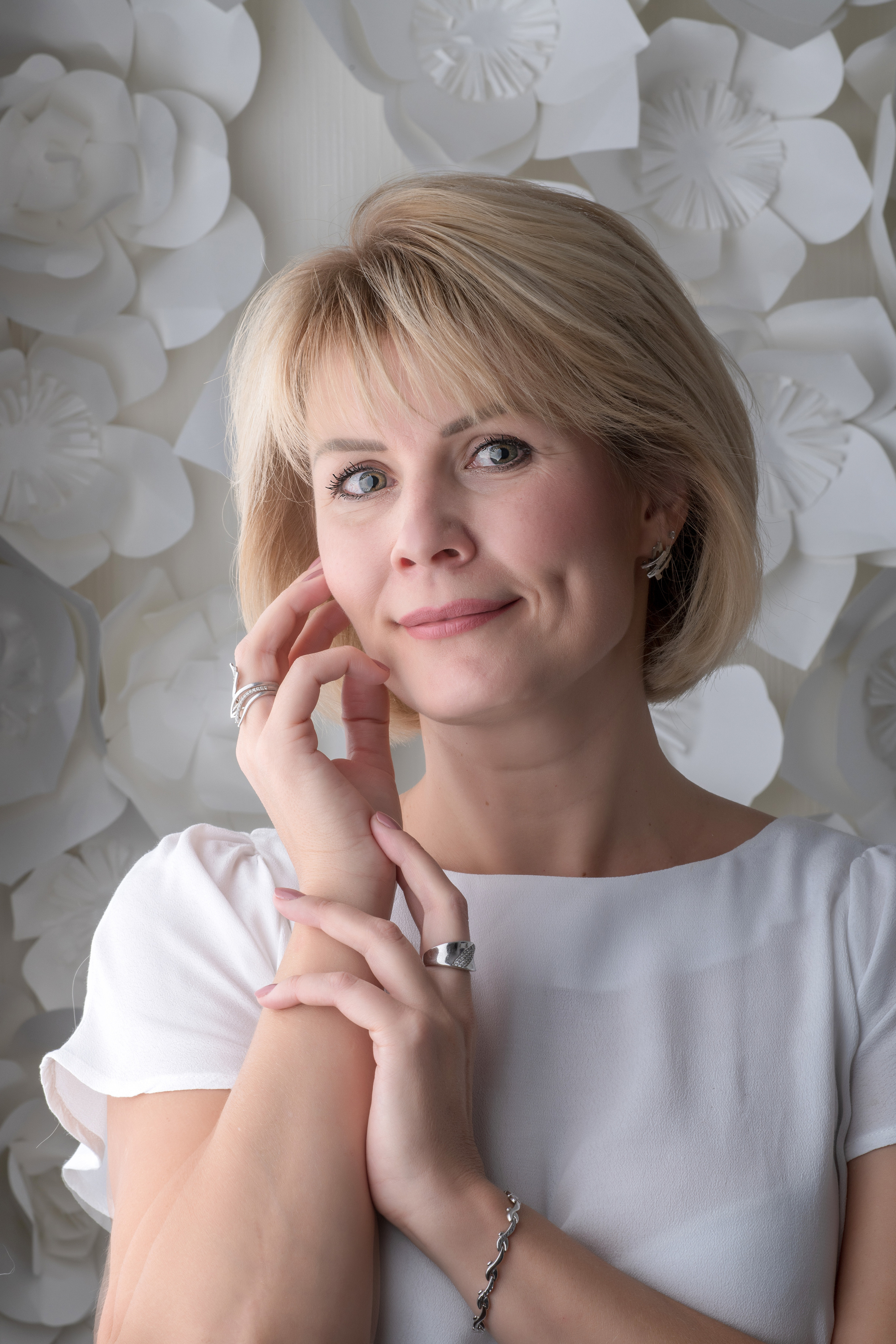 портрет молодой женщины стоящей на фоне белых цветов в студии