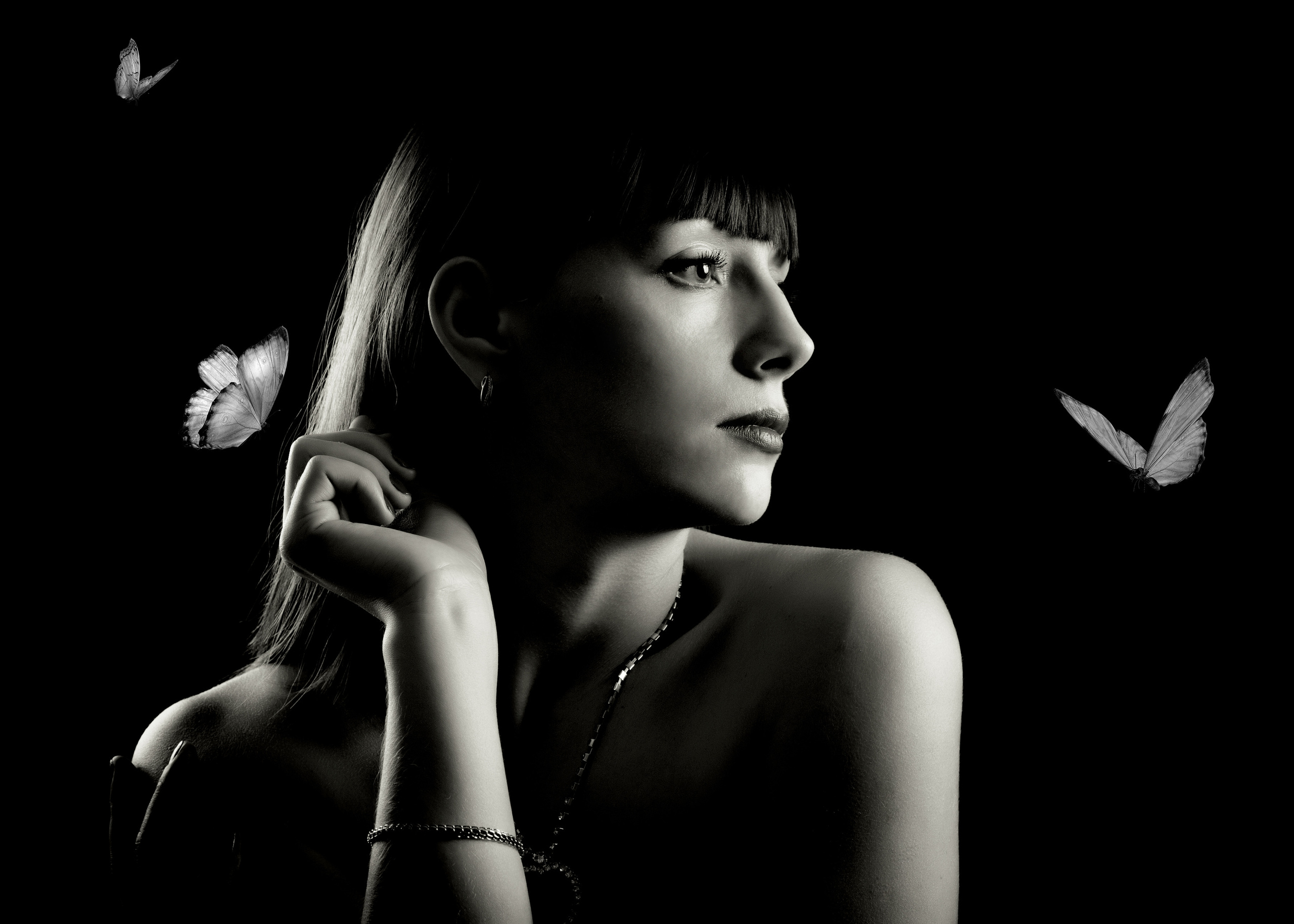 черно-белый портрет в профиль девушки в низком ключе с парящими рядом бабочками
