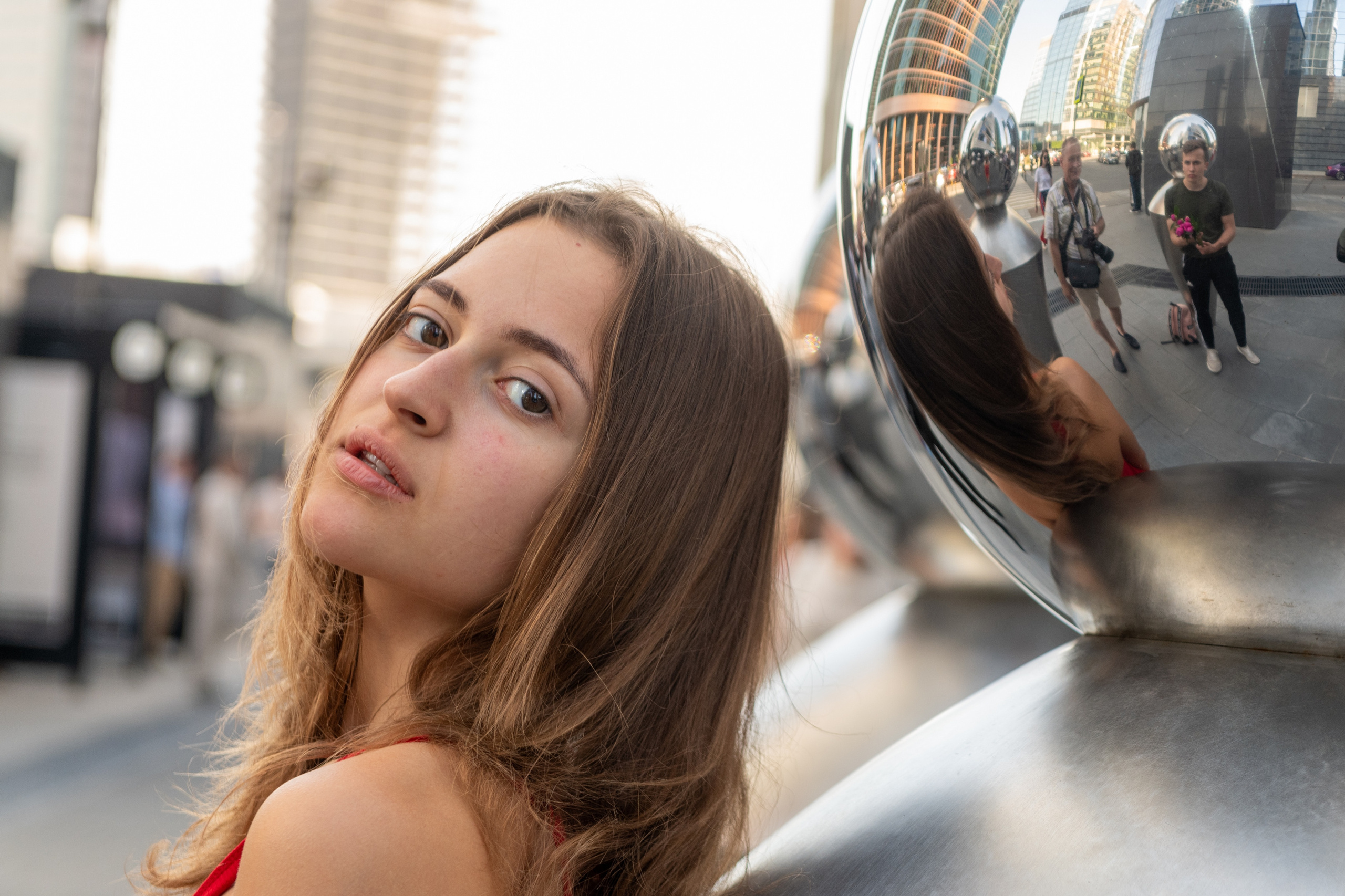 Портрет девушки стоящей в Москва-Сити рядом с зеркальным шаром в котором есть отражение