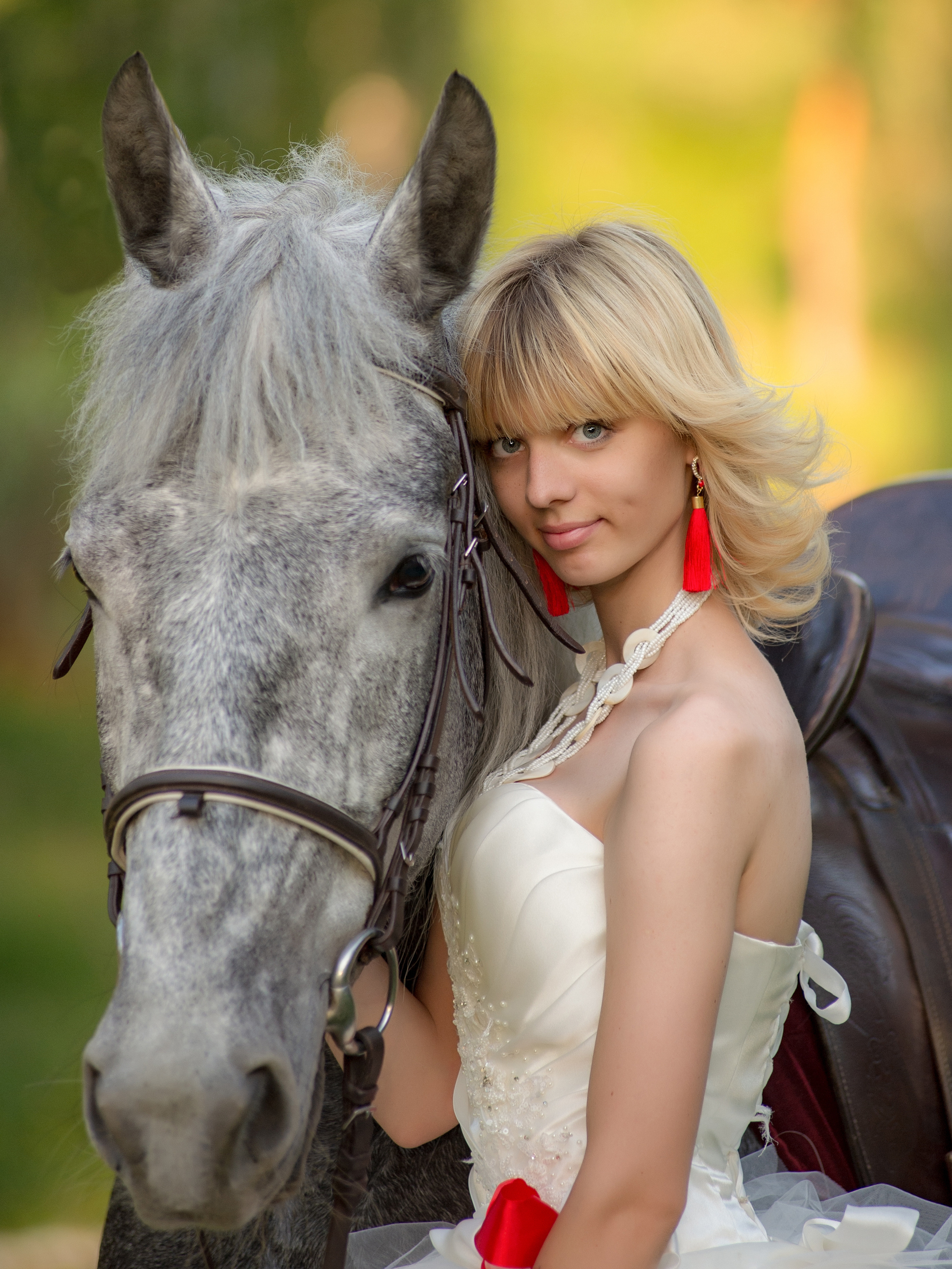 Портрет девушки с красными серьгами и в белом свадебном платье рядом с ее любимым конем