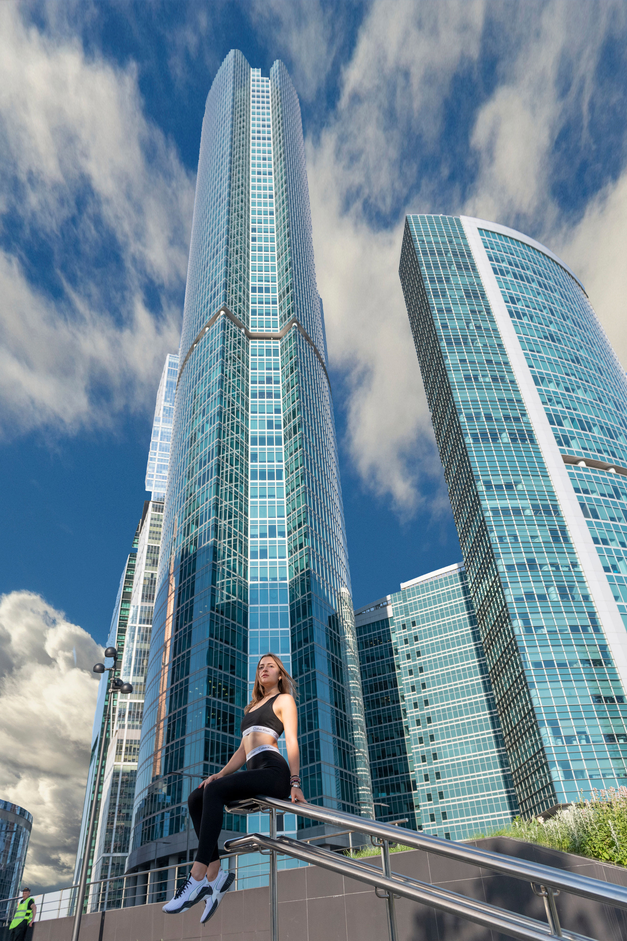 Москва-Сити с сидящей на периллах лестницы на фоне высотных зданий и голубое небо с облаками