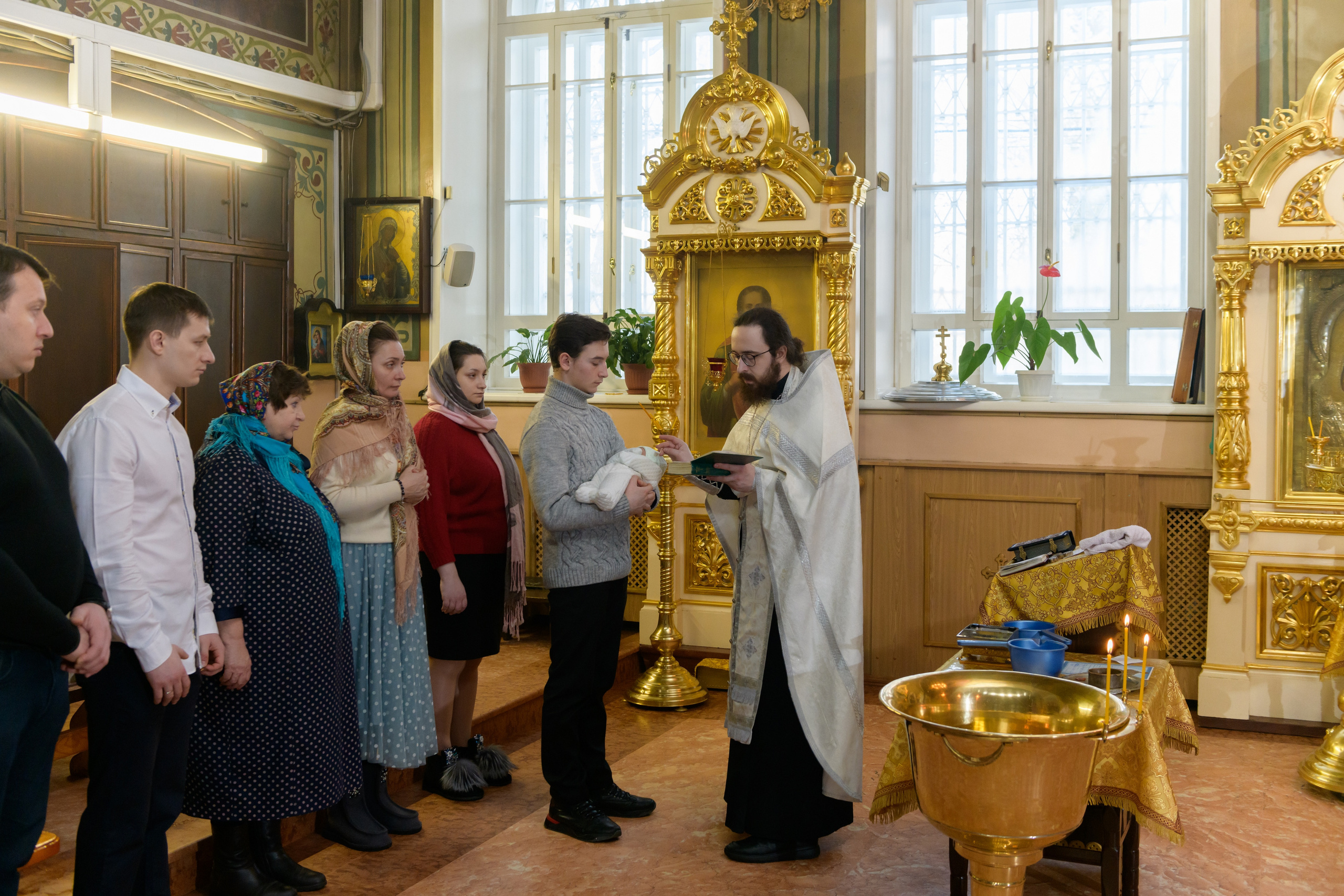 Крестины в церкви. Священник проводит таинство крещения младенца в церкви читая молитвы