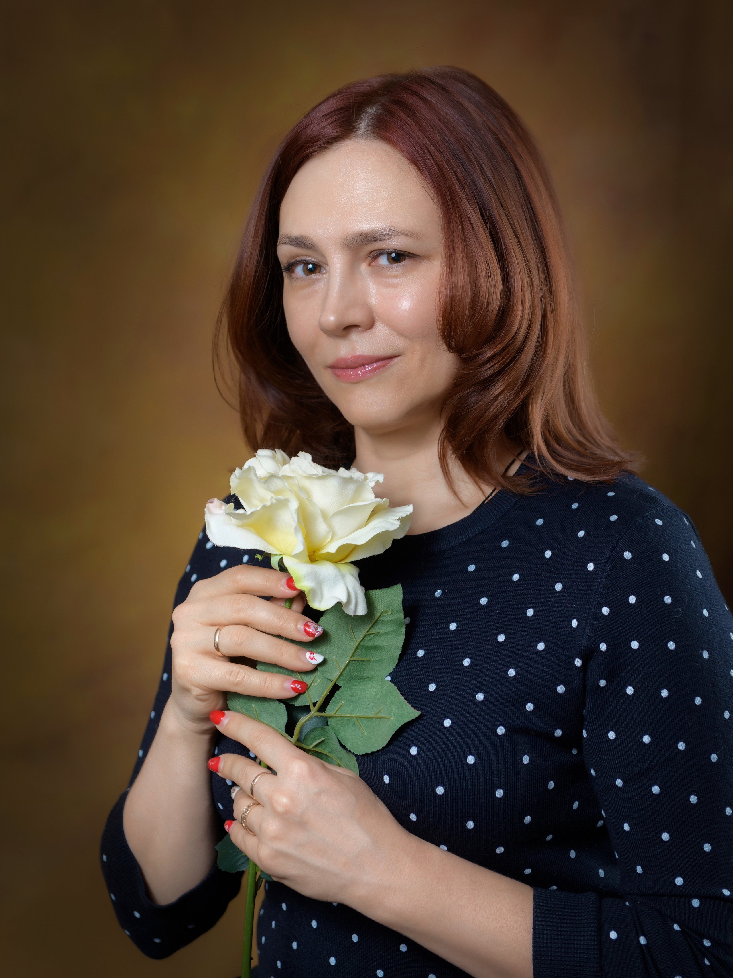 портрет взрослой женщины в студии в руках держит цветок розы