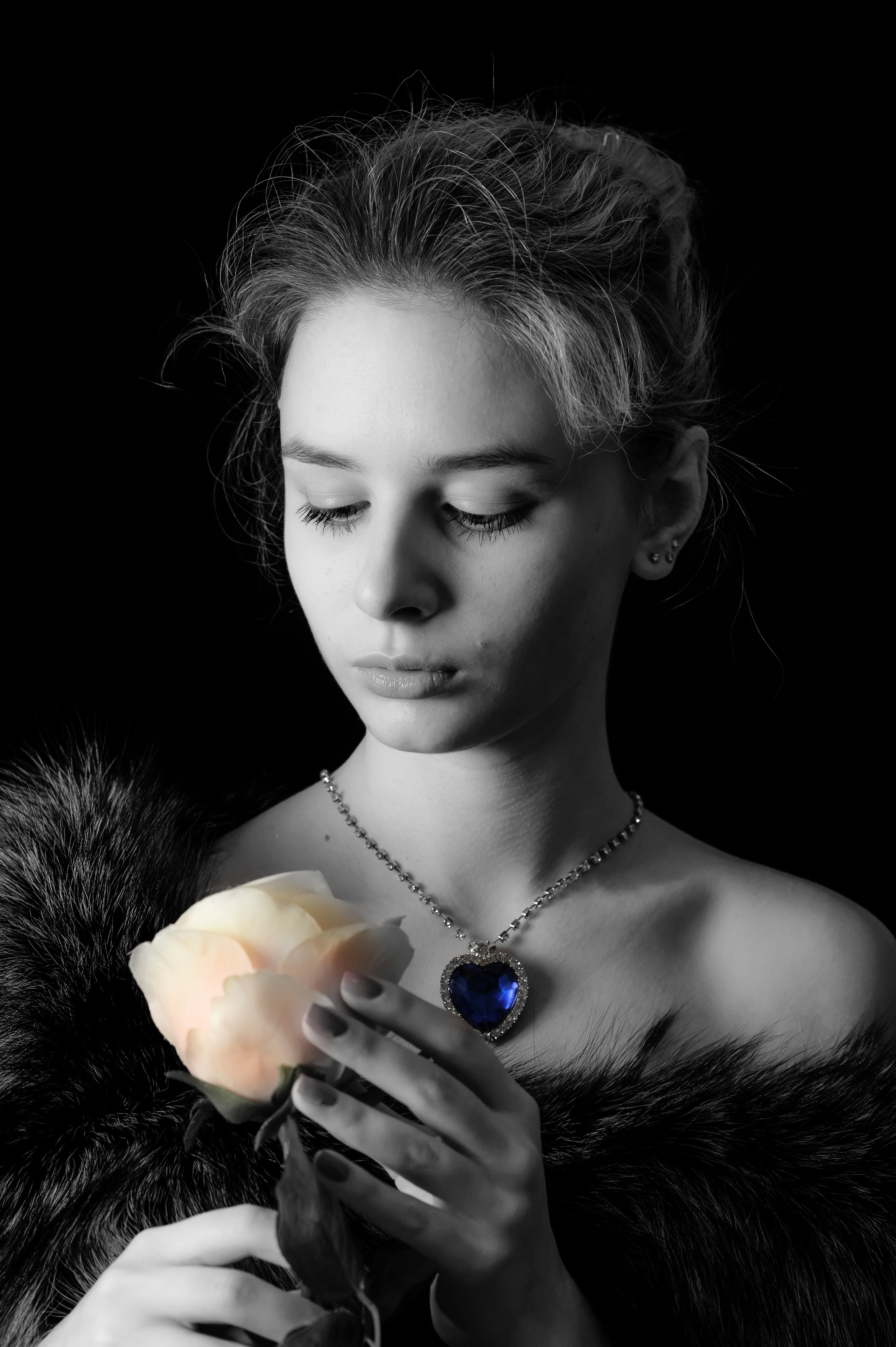 черно-белый портрет девушки в руках держит цветок розы и смотрит на него