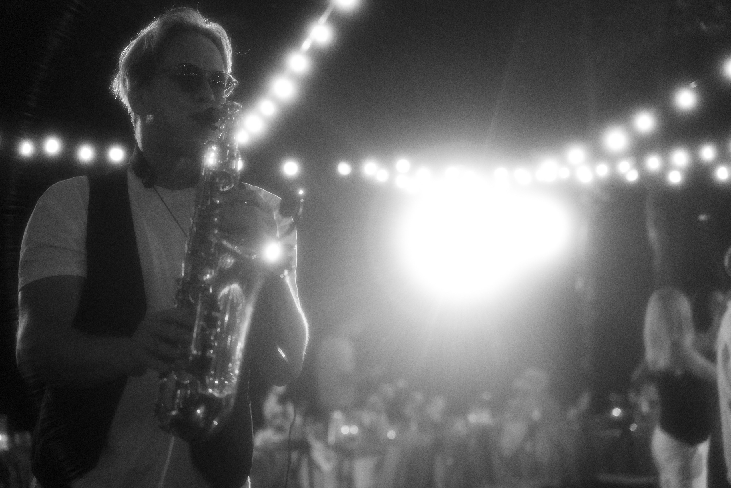 Чёрно-белый снимок саксофониста как он играет на свадьбе для гостей 