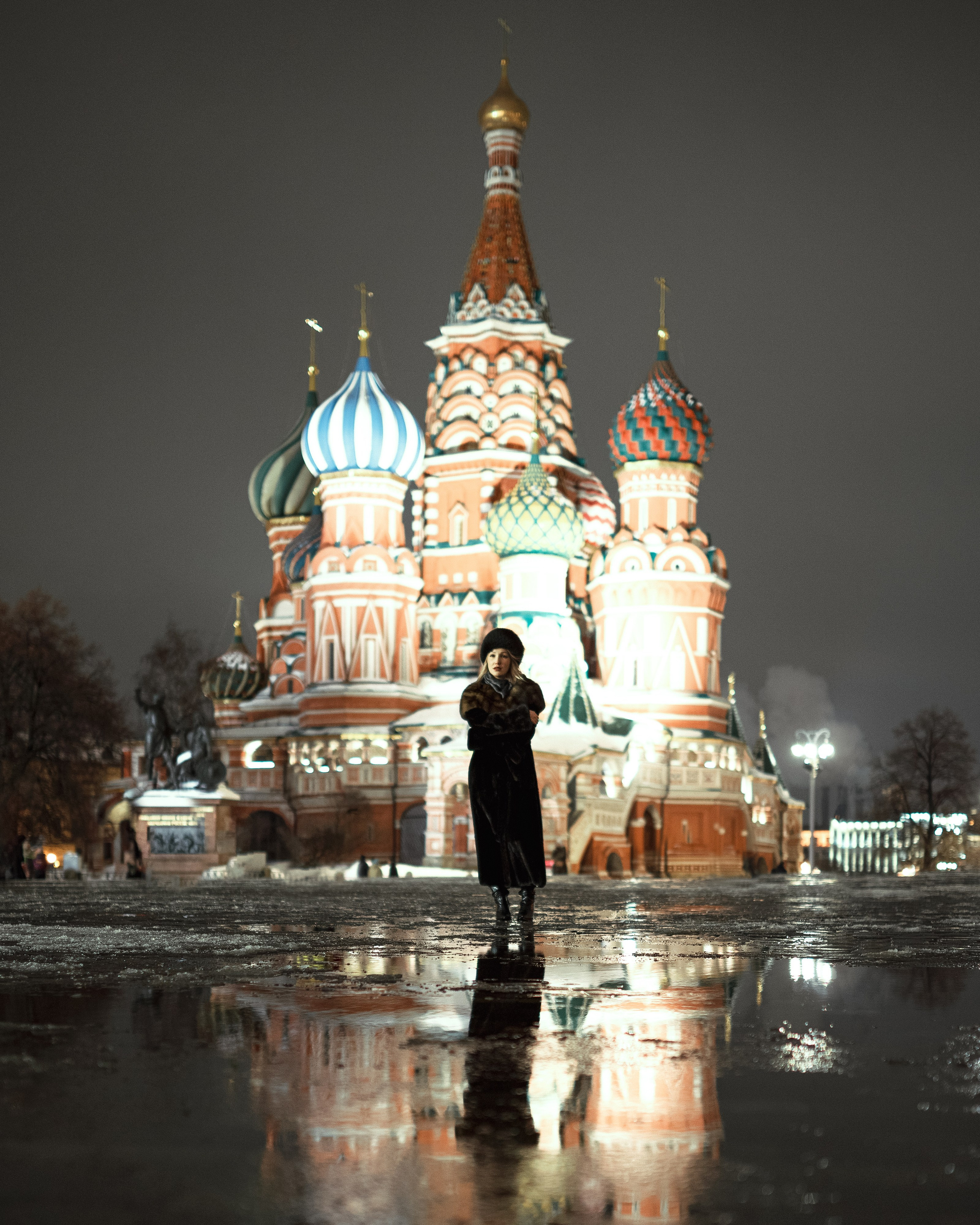 Девушка в шубе стоит напротив собора на красной площади в Москве 