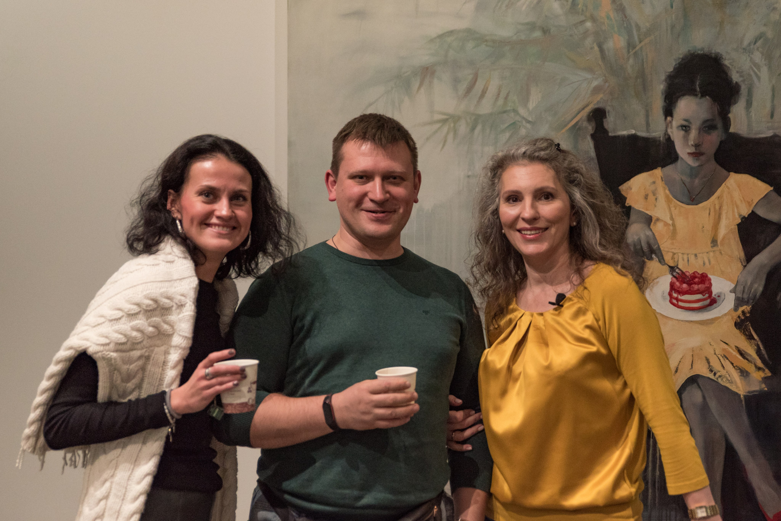 Семинар по психологии. Женщина, мужчина и ведущая Ирина Иванова, позируют напротив большой картины.