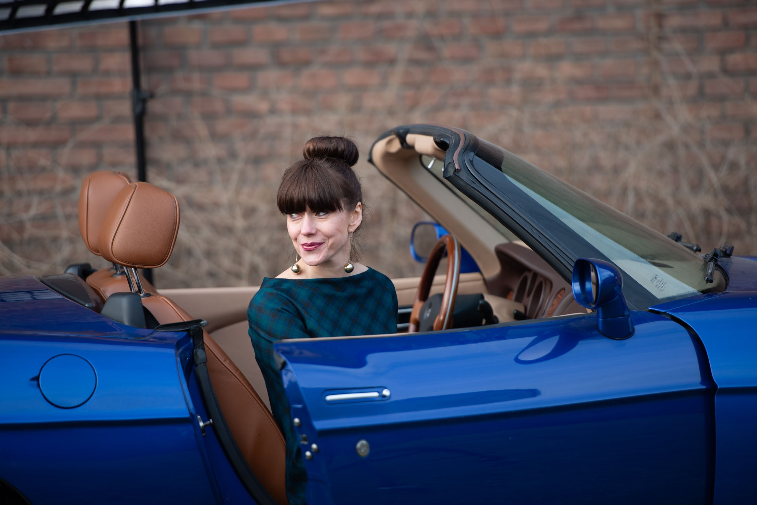 На снимке запечатлена певица Светлана Бень (Беня) в винтажном стиле. У нее темные волосы, собранные в высокий пучок. На ней темно-зеленое платье в сине-черную клетку.  Она сидит в синем кабриолете, с коричневым кожаным салоном и смотрит вдаль. Фотография выполнена в приглушенных тонах, фокусируется на стиле и выражении лица артистки