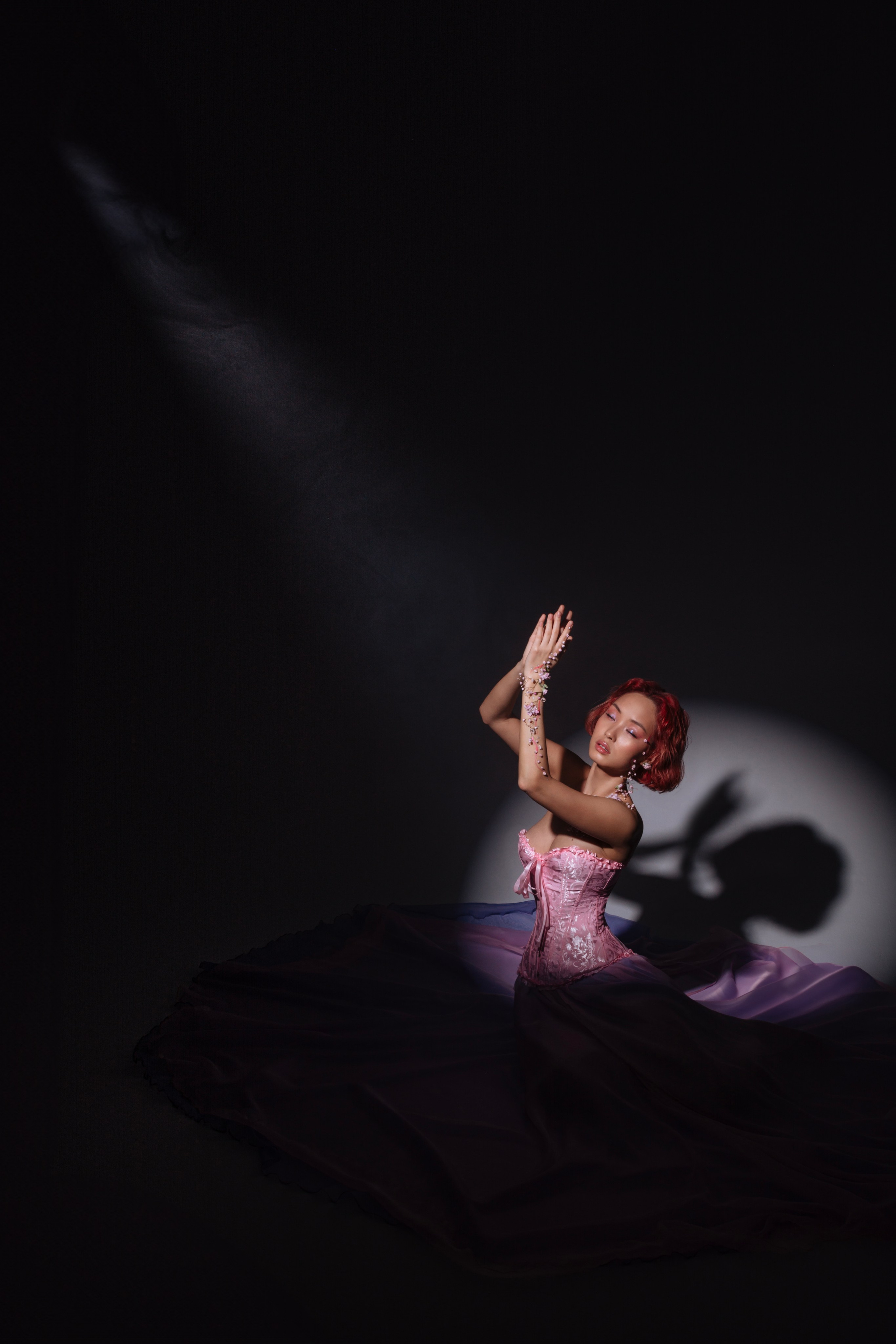 Мечтательный взор прекрасной азиатской девушки в цветочных украшениях на фоне круга света, ее взгляд устремлен вдаль, символизируя ожидание весны.