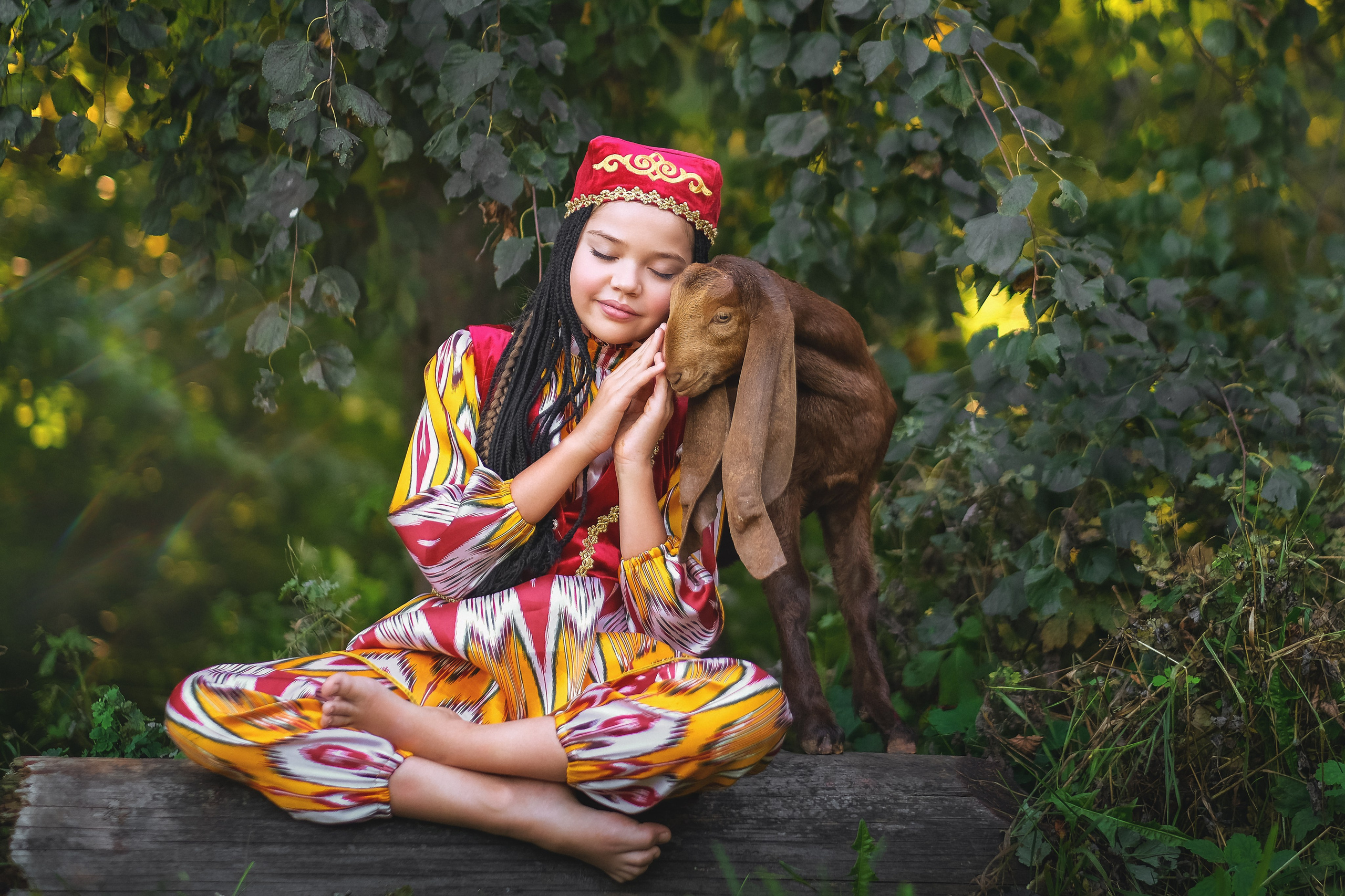 Девочка в национальном костюме обнимает козлика