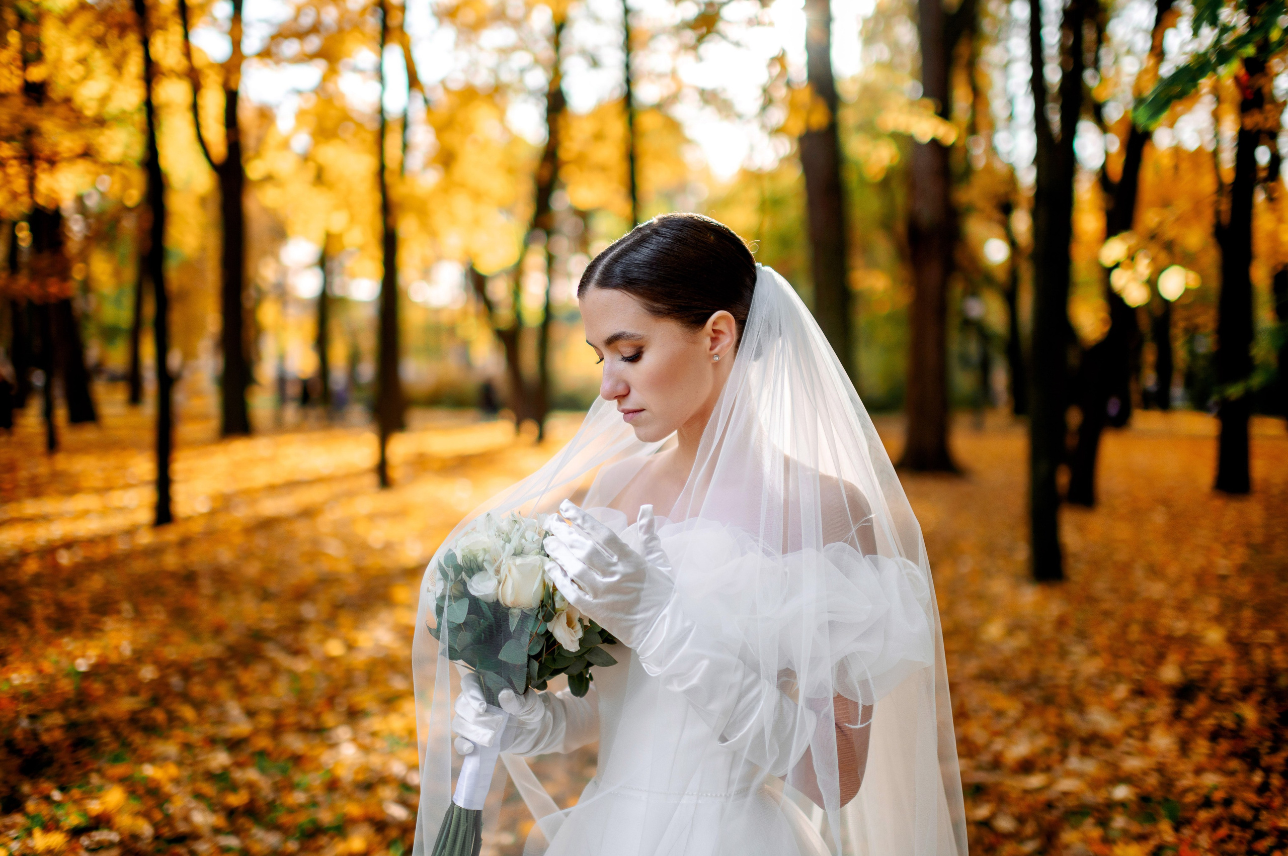 Портрет элегантной и аристократичной невесты в осеннем парке в солнечных лучиках.