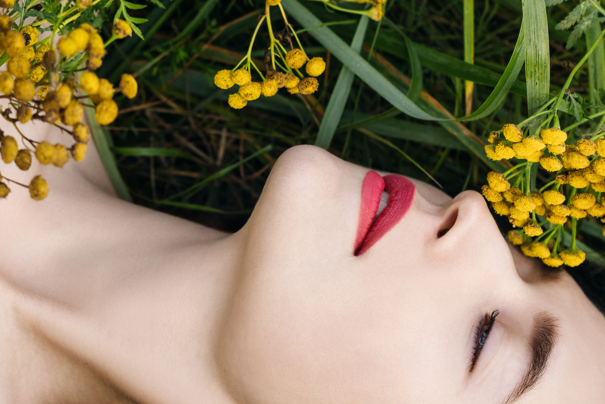 красивая девушка нюхающая желтые цветы с чистейшей и нежной белой кожей лежащая в траве 