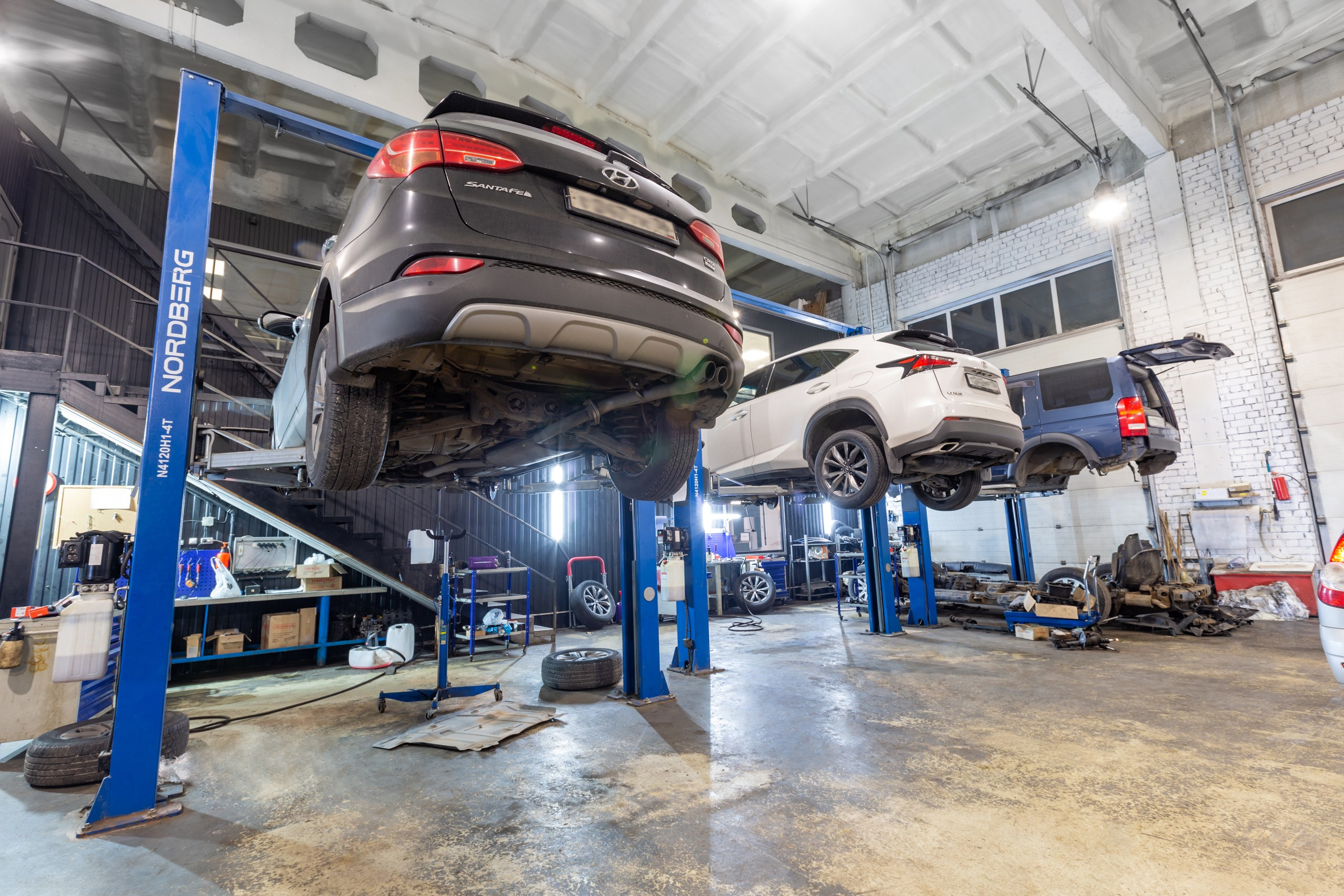 Три автомобиля на подъемниках в авторемонта. Вид снизу.