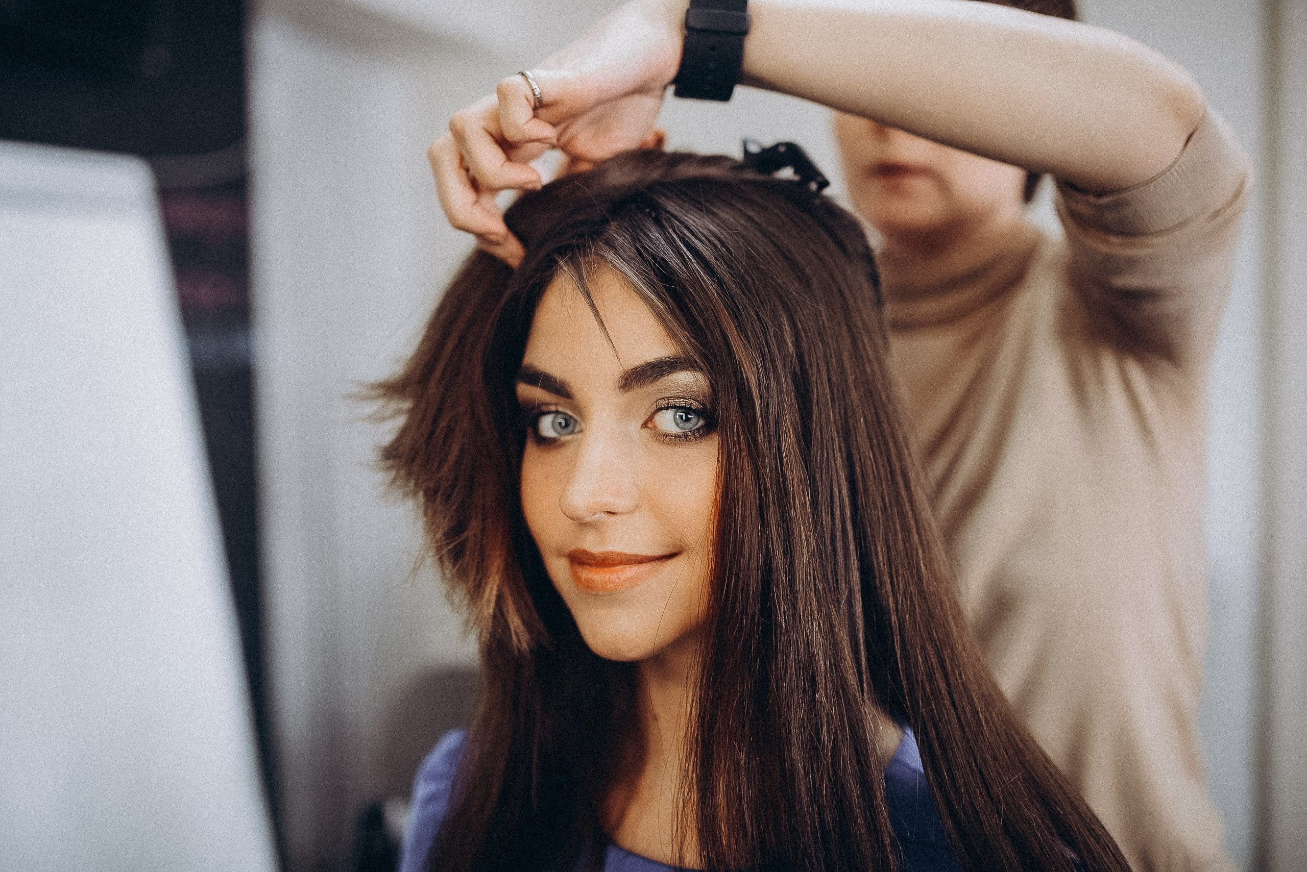 Стилист создает объемную укладку с локонами, подготовка к дефиле в гримерной.