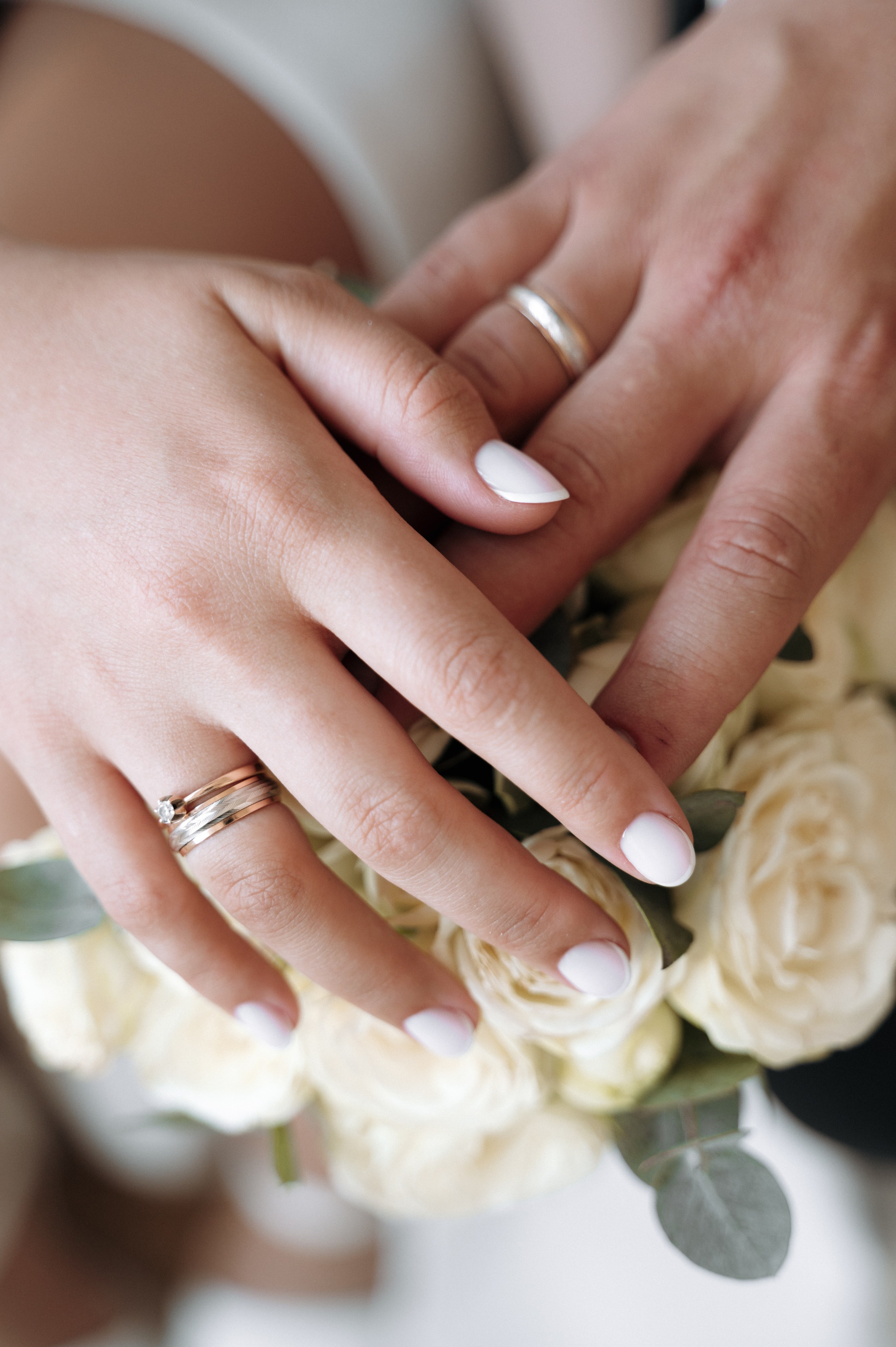 руки молодоженов на фоне свадебного букета