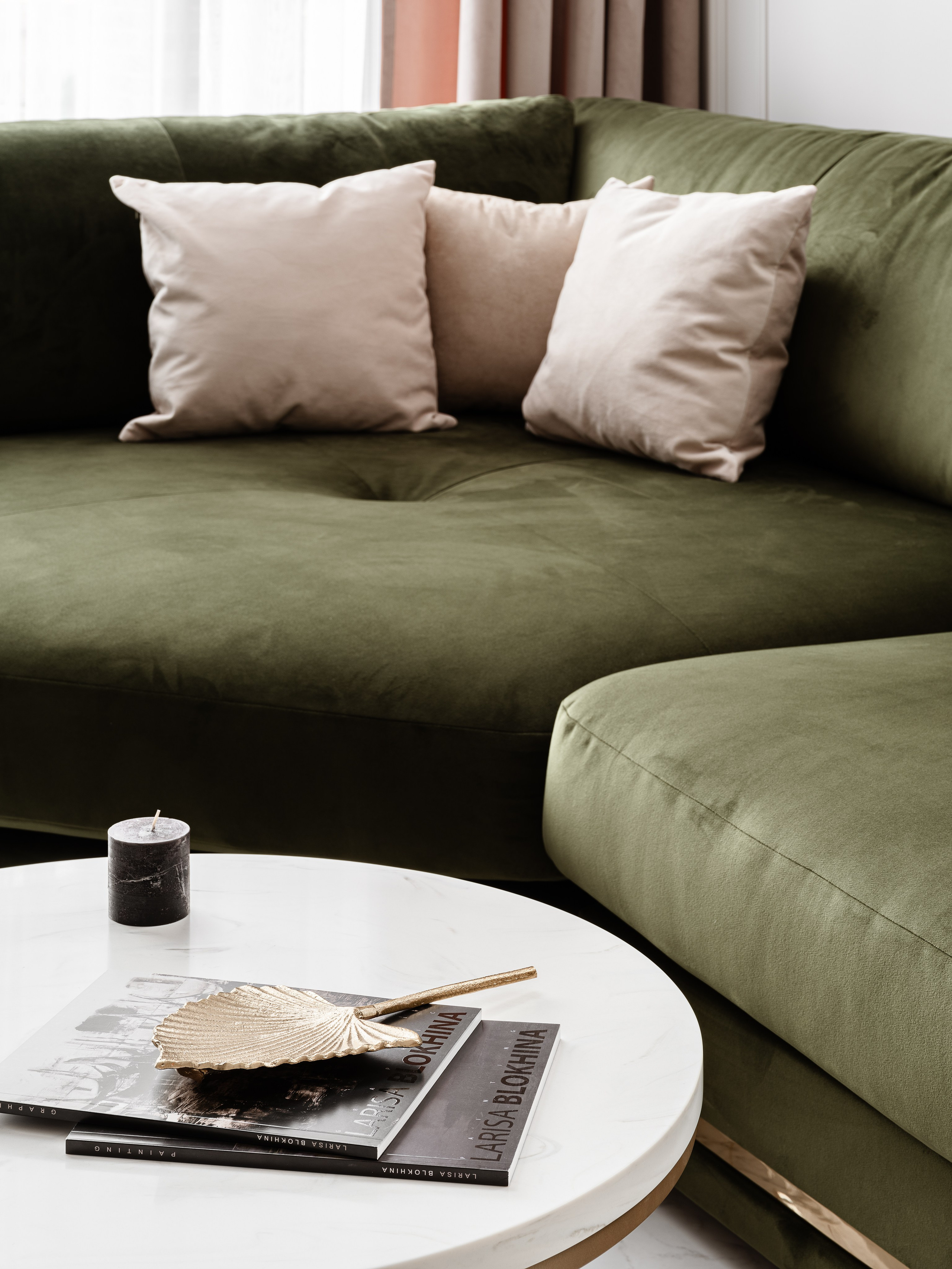 Уютная гостиная с зеленым бархатным диваном и бежевыми подушками, белый круглый столик с декором, мягкий свет и акцентные шторы, изысканный интерьер, дизайнер Евгения Ермошина, фотограф Сергей Денисенко.