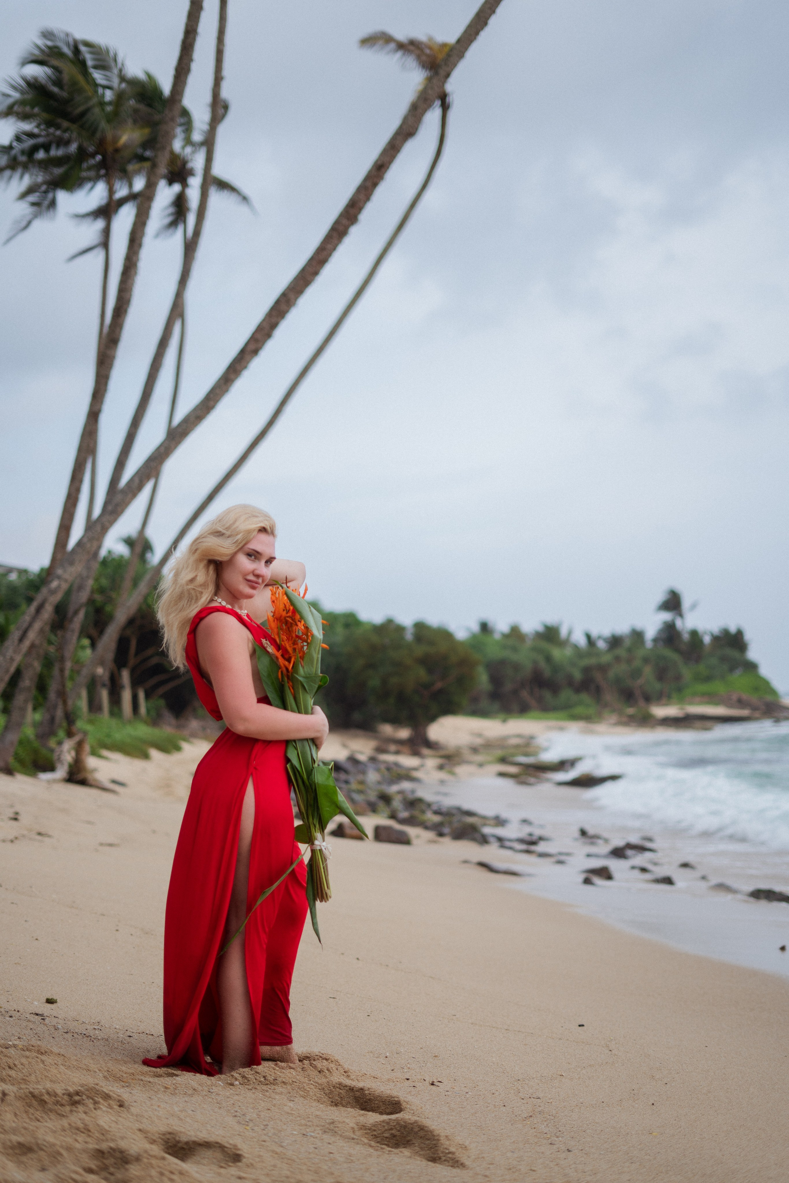 a blonde in a red dress enjoying the view of the ocean