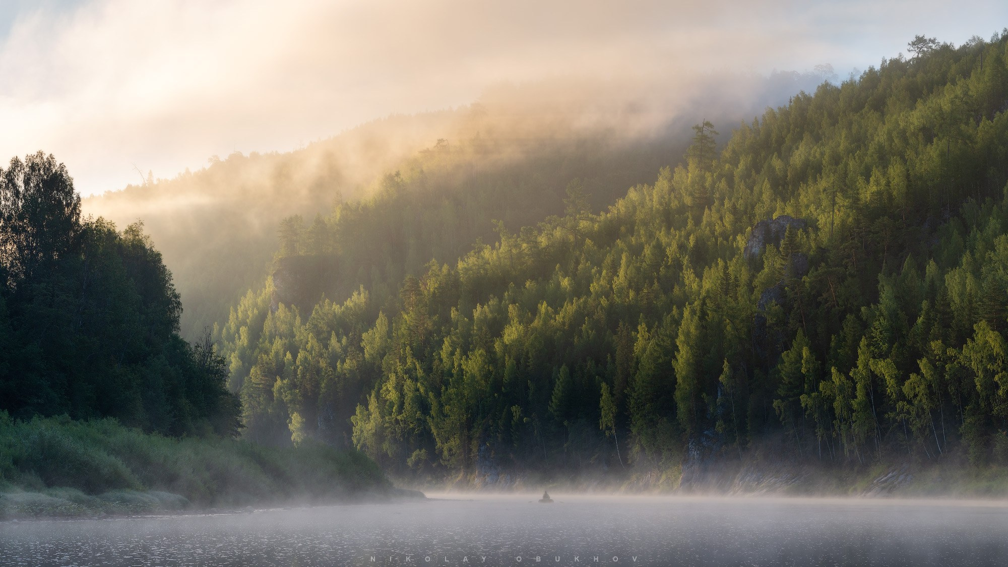 Утренний туманный пейзаж на реке Чусовая. Одинокая лодка плывет по реке с туманной дымке