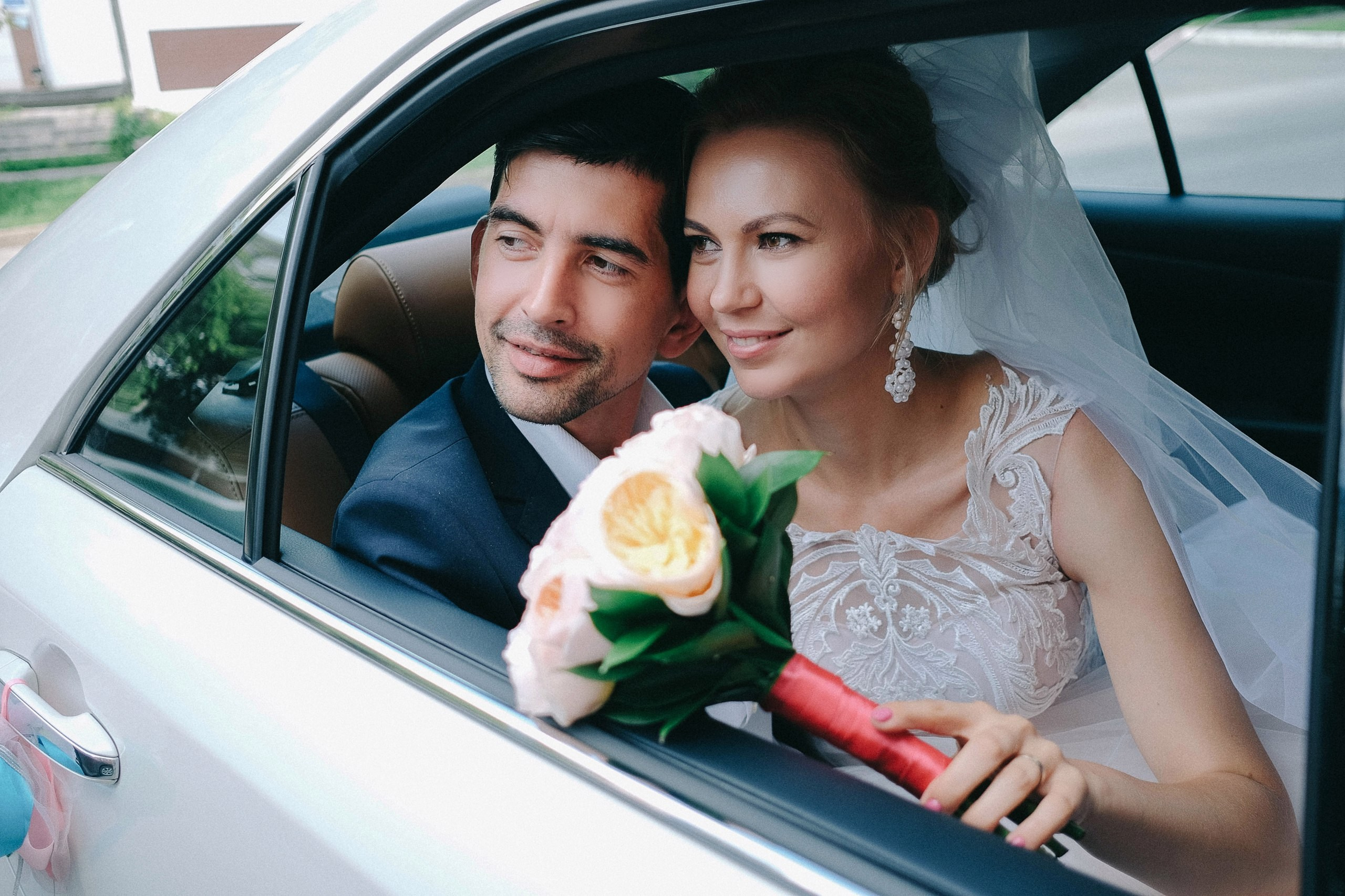 Счастливые молодожены смотрят из окна машины