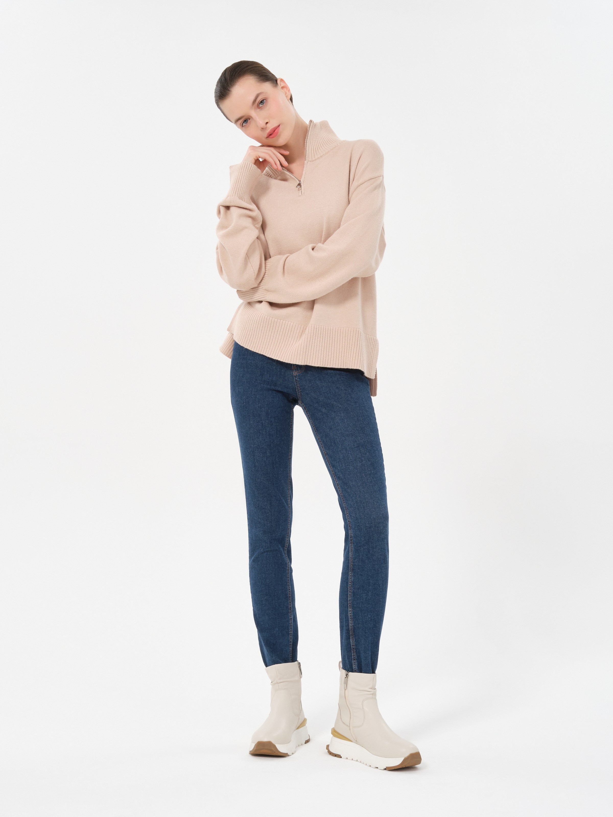 Женщина в светлом свитере и светлых ботинках